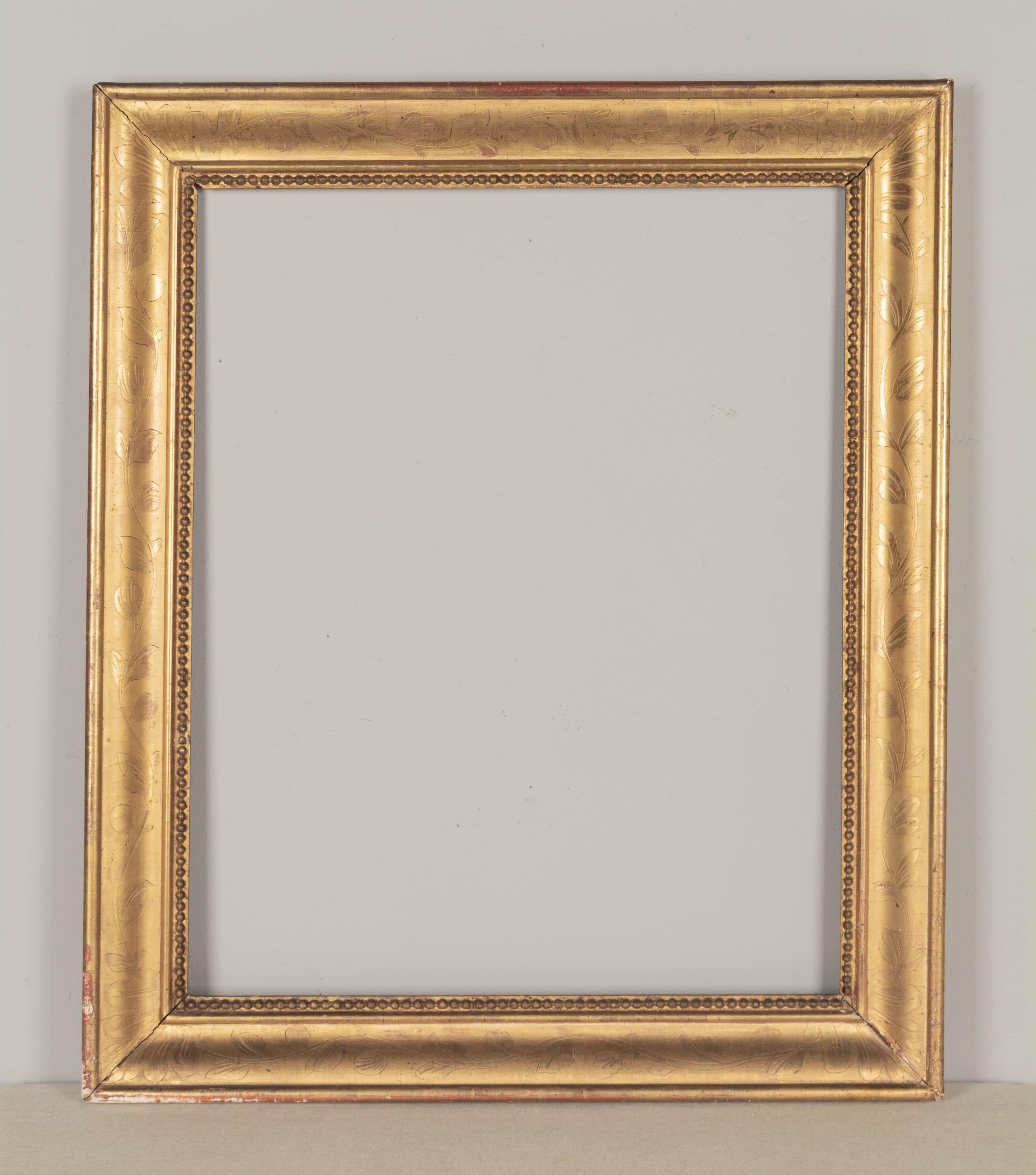Cadre en bois doré français du 19e siècle, avec un décor de vignes incisé et une bordure intérieure en perles. La finition dorée à chaud est en bon état avec quelques pertes sur les bords extérieurs, de légères séparations de coins et des retouches