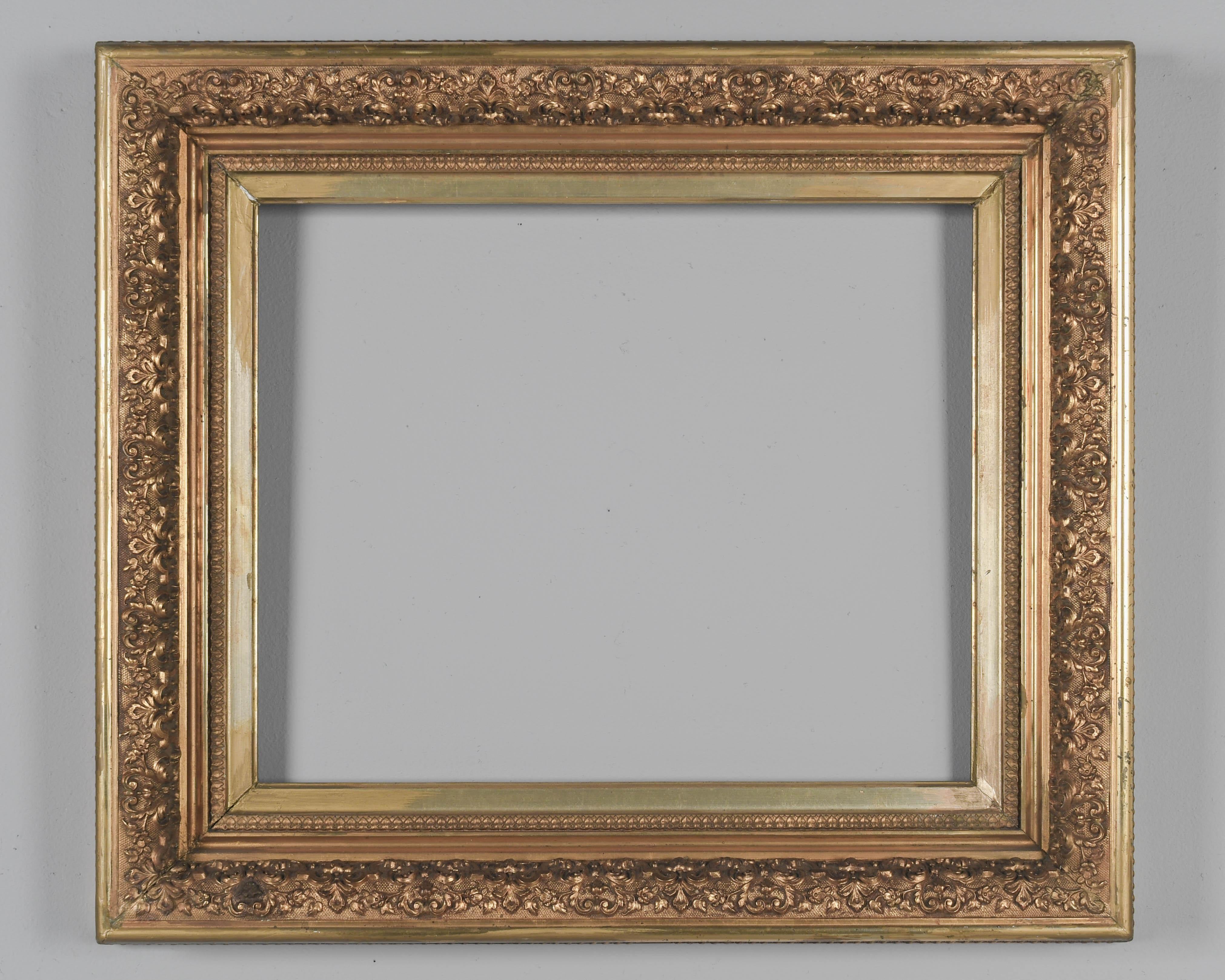 Marco francés de madera dorada del siglo XIX con decoración floral en relieve y borde exterior de cuerda. El cálido acabado dorado está en buen estado, con algunas pérdidas, ligeras separaciones en las esquinas y pequeños retoques. Puede colgarse