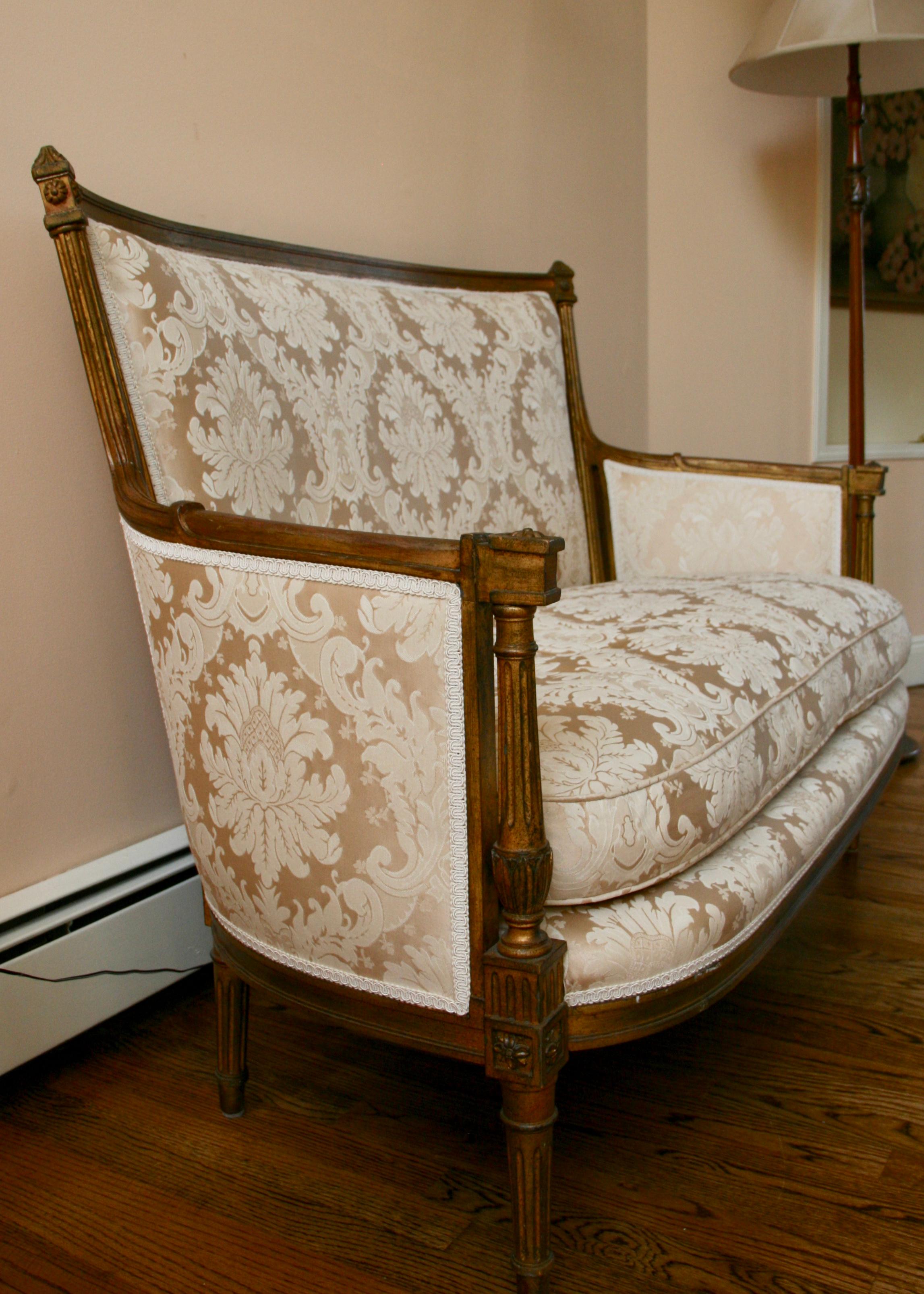 Un canapé français de style Louis XVI en bois doré avec une tapisserie blanche en damas neuf. Structure solide en bon état d'origine.