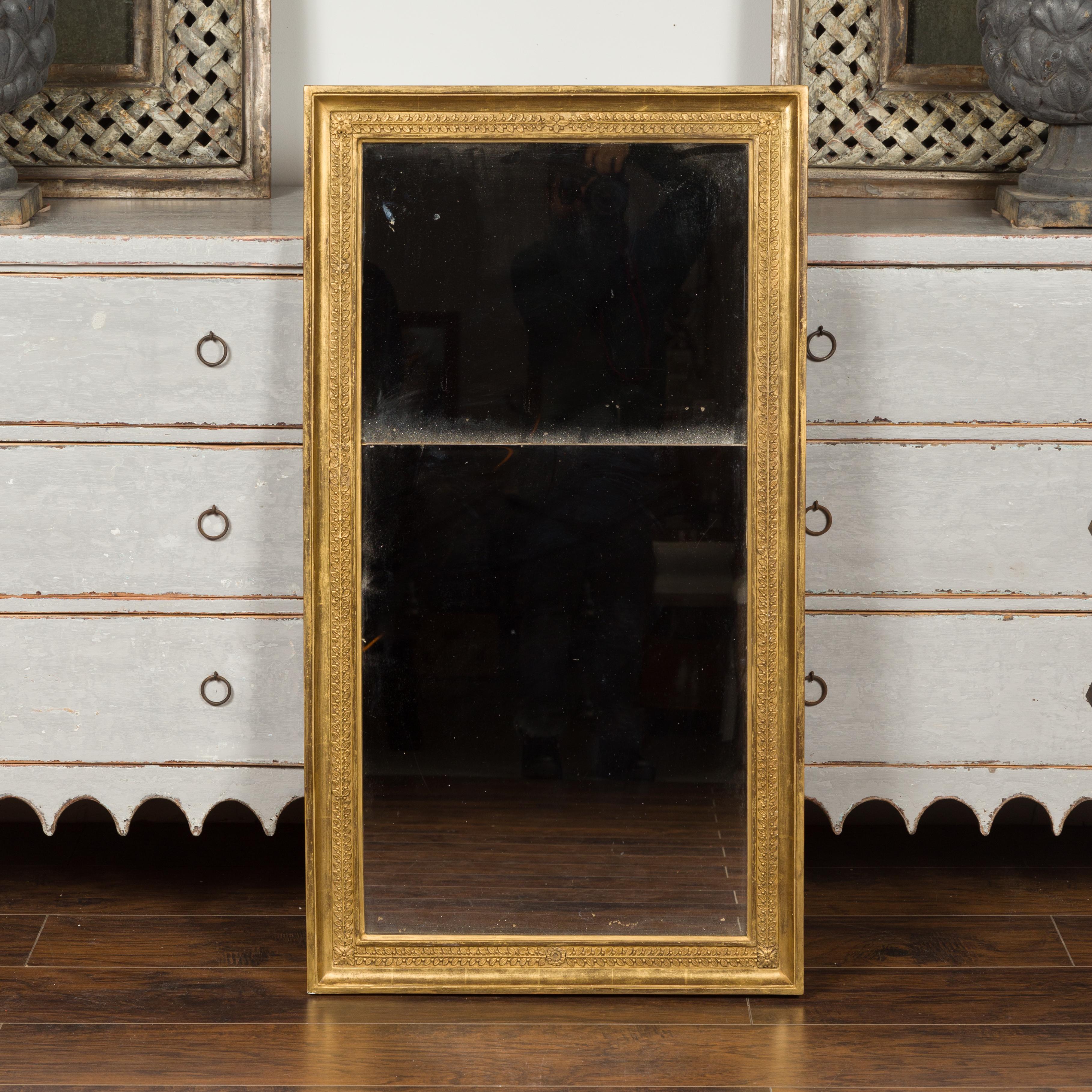 A French giltwood split glass mirror from the turn of the century, with foliage and rosette motifs. Created in France at the turn of the 19th to 20th century, this split glass mirror features a giltwood frame, adorned with delicately carved foliage