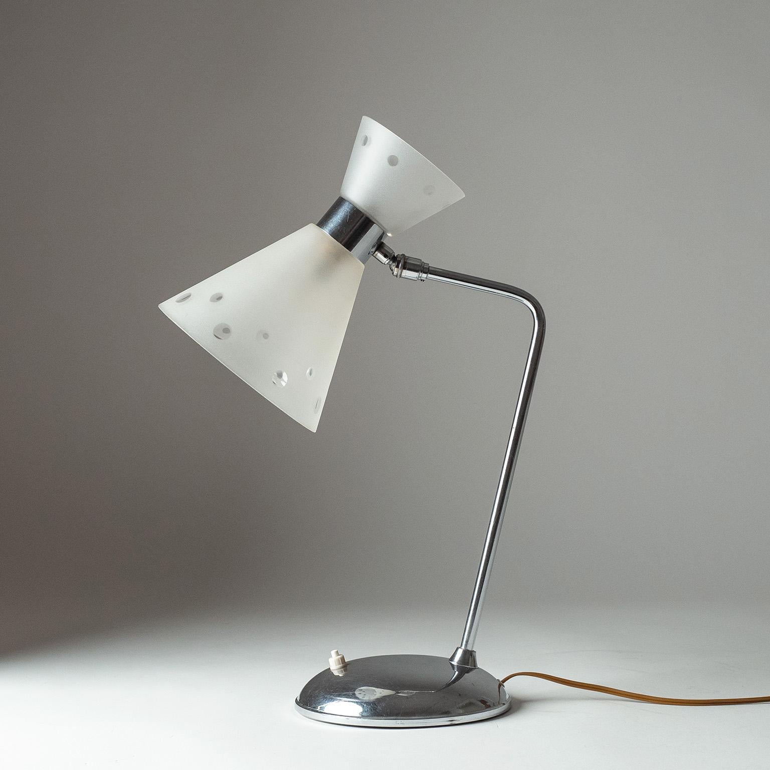 Rara lámpara de escritorio francesa de mediados de siglo de la década de 1950. Base cromada y vástago acodado con pantallas de cristal cónico esmerilado con lunares transparentes. Una toma B22 original de latón.

Medidas: Altura 45 cm (17,5″),