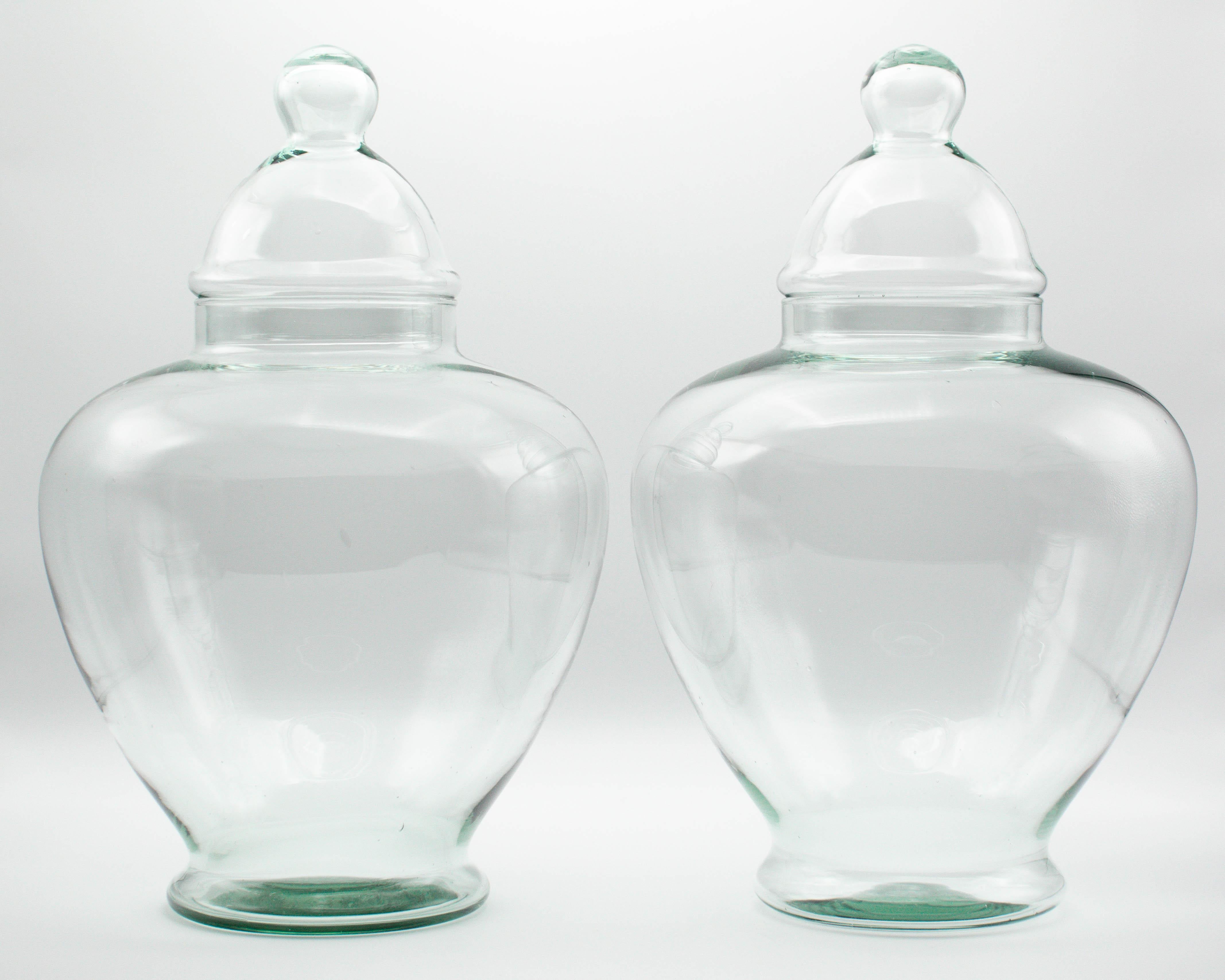 A pair of French blown glass lidded apothecary or candy jars. Smooth urn shaped form with domed lids. Large and light weight, perfect for jelly beans or macerated fruit. Purchased from a confiserie, or sweet shop, along with many glass jars of