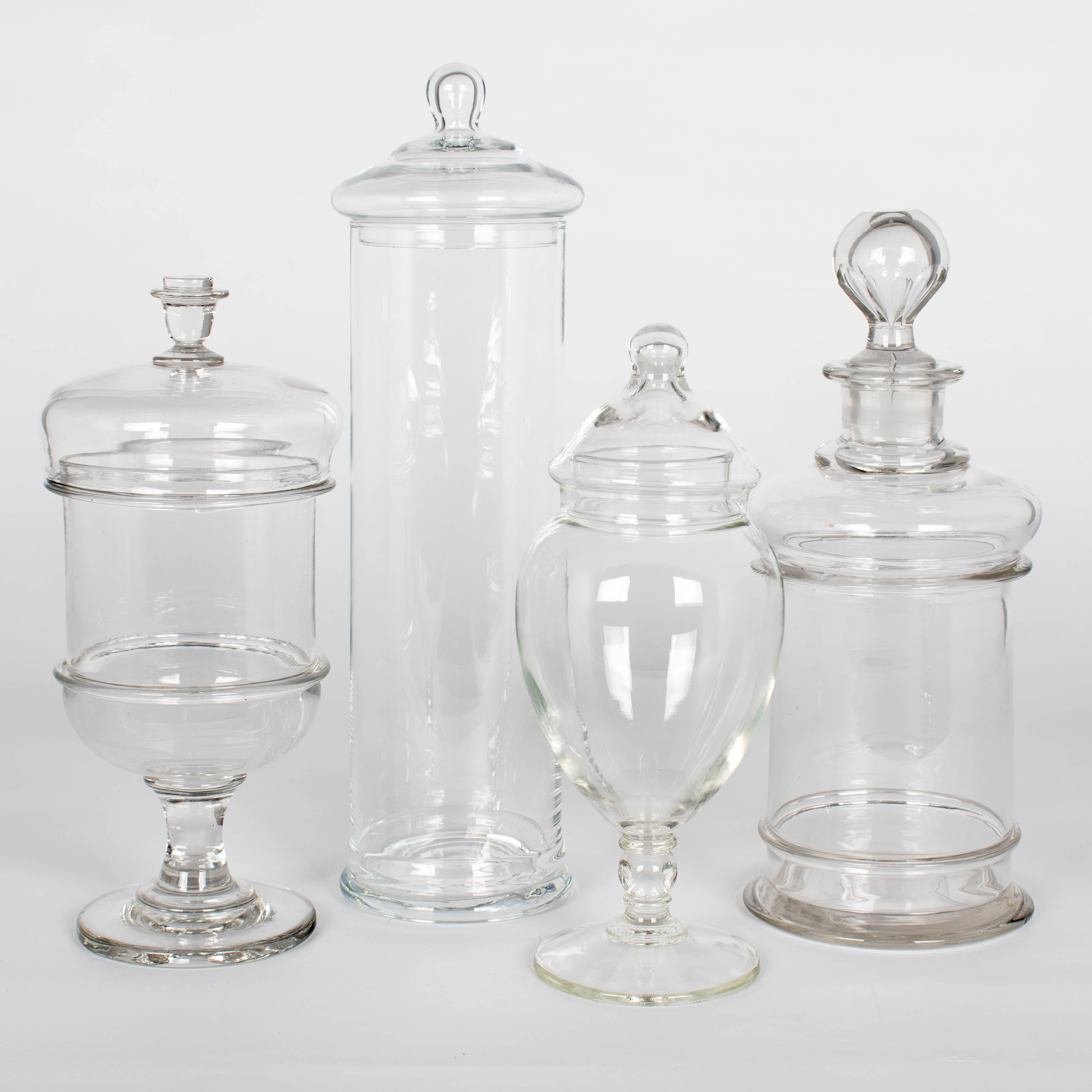 Un set di quattro barattoli da farmacia o da caramella in vetro soffiato a mano. Forma liscia con pomello sul coperchio. Perfetti per essere utilizzati come contenitori per il bagno o per esporre conchiglie, biglie o pietre in modo decorativo.
