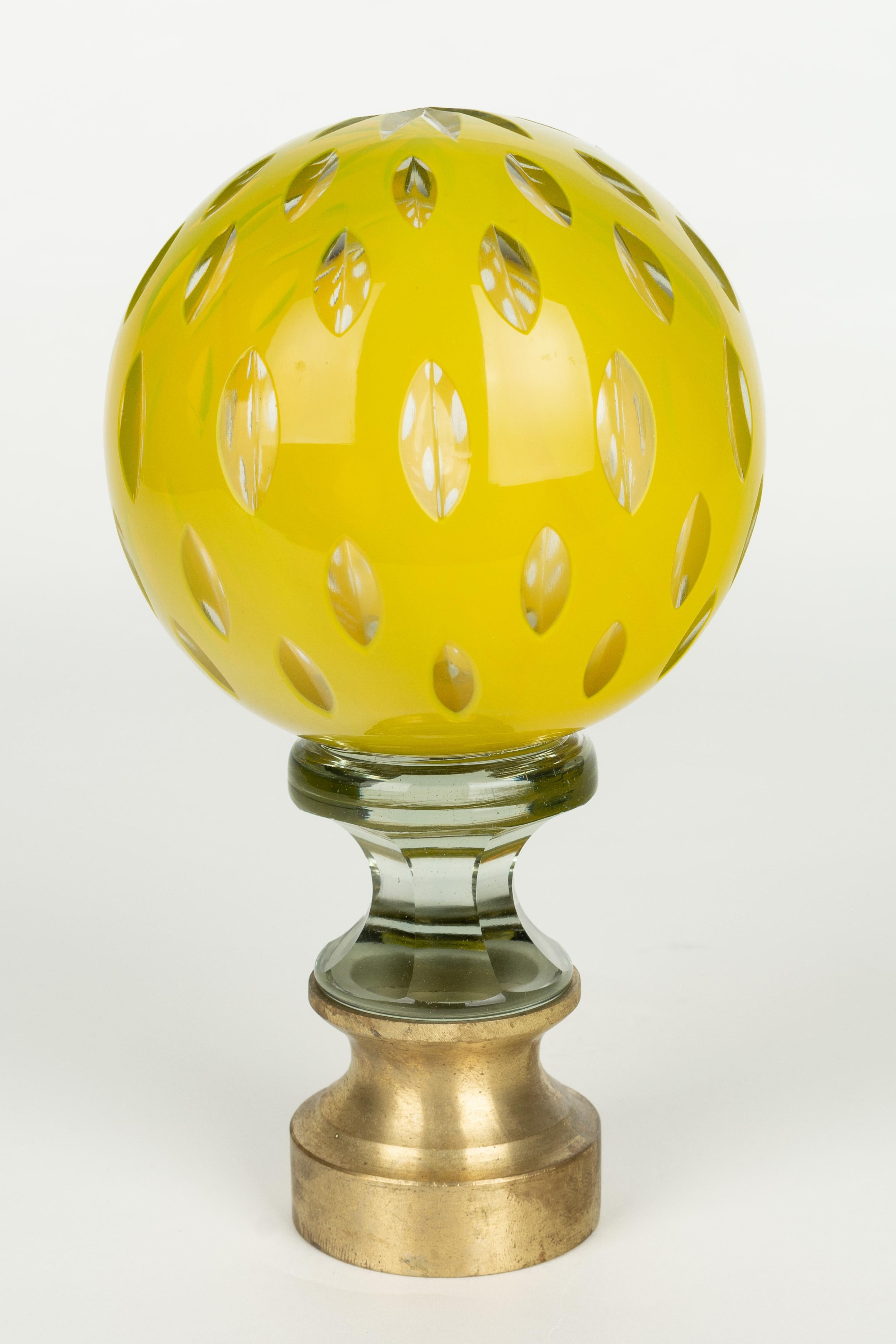 A French crystal newel post finial or boule d'escalier. Made of two layers of cased glass with the yellow glass surface cut to reveal clear glass underneath. Brass hardware base. These wonderful finials were used as decorative elements at the bottom