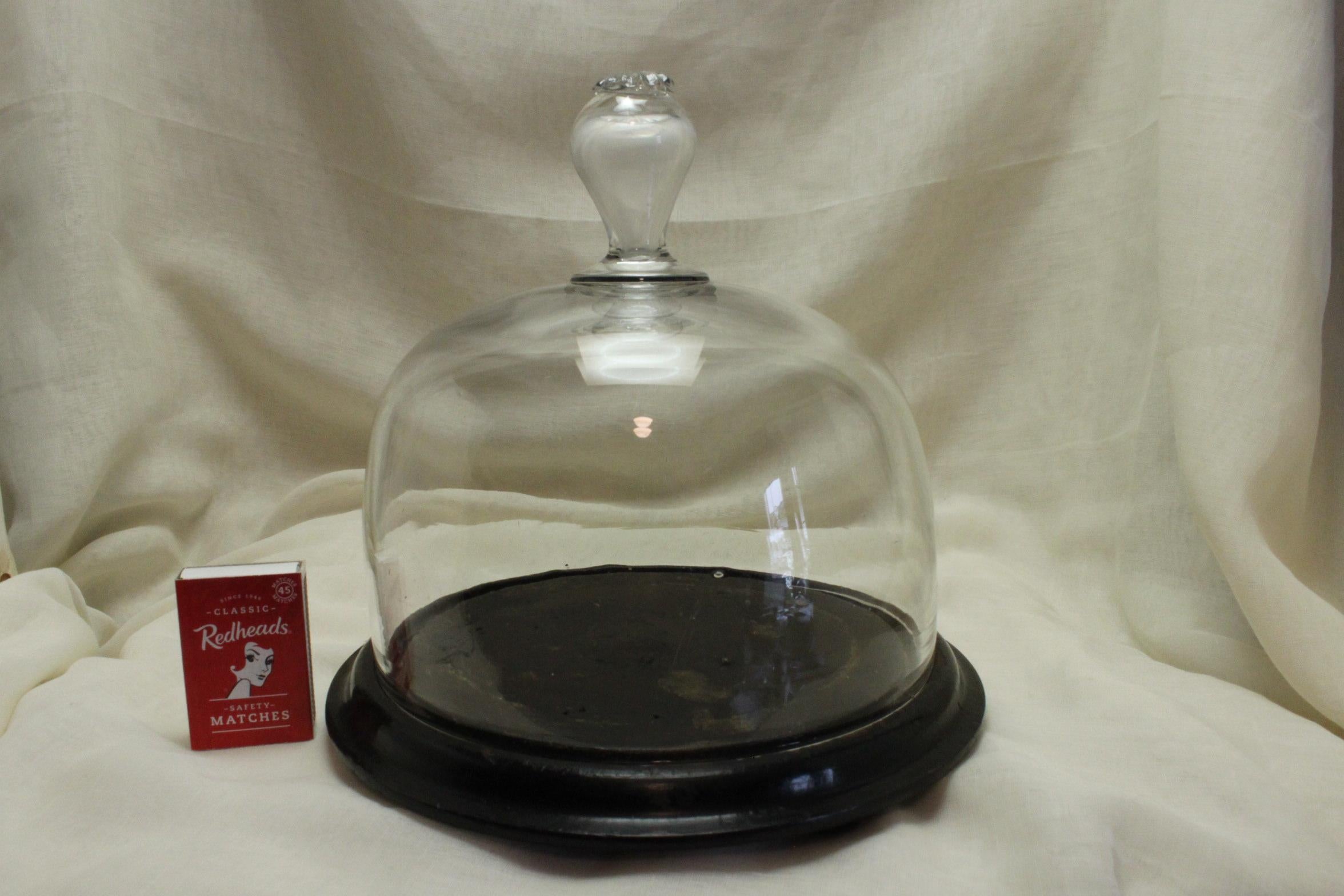 This French glass food dome or cloche, sits on a wooden stand and was used to display or cover food. The hand blown dome measures 180 mm (7.25 inches) in height and has a diameter of 175 mm (7 inches). Sitting on the stand the height is 195 mm (7.75