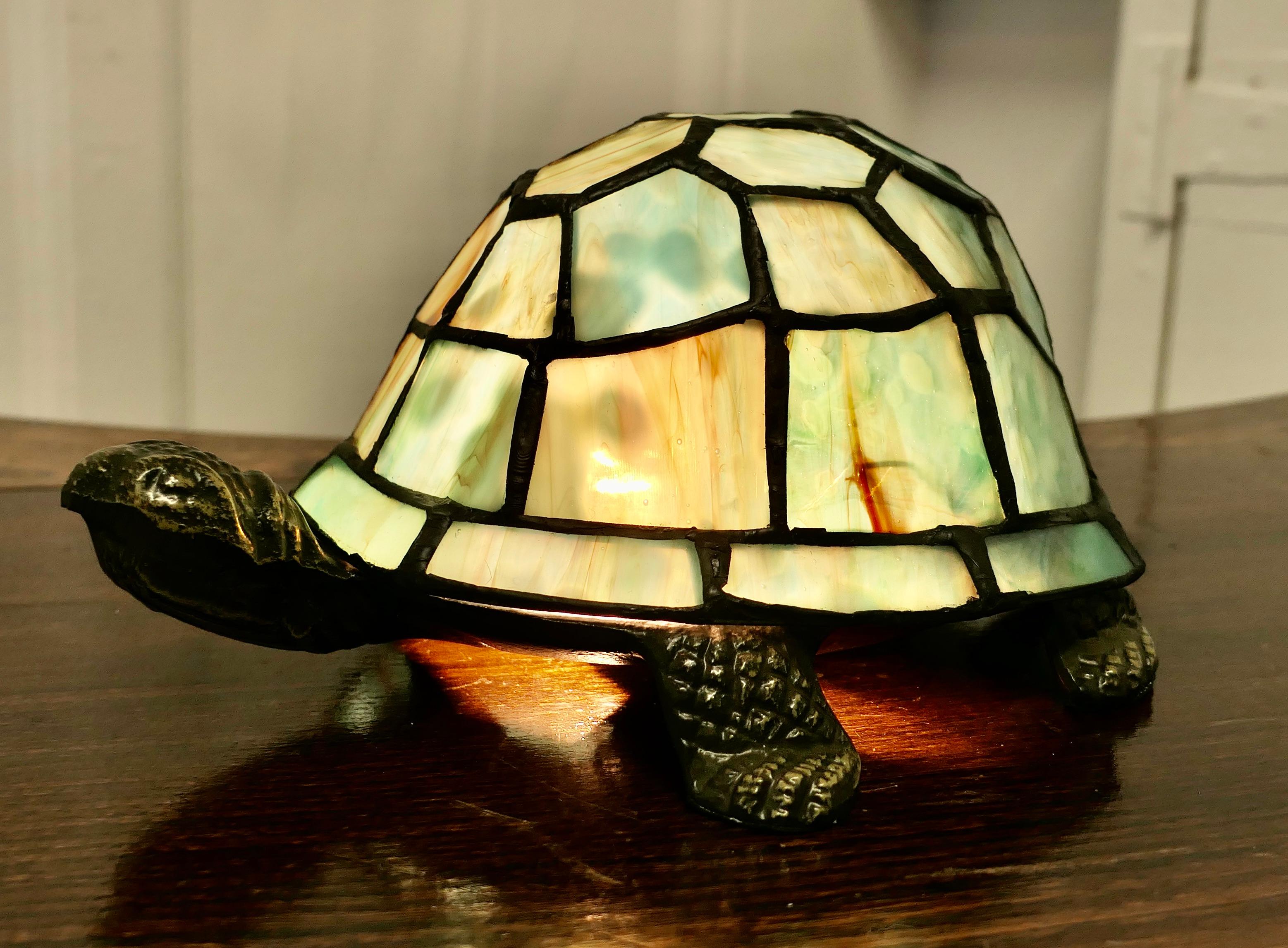 French Glass Tiffany Style Lamp in the form of a Tortoise

This charming lamp has a heavy metal base the shade is made in leaded glass which forms the shell of the tortoise in shades of green and amber
The lamp is in good condition, all working and
