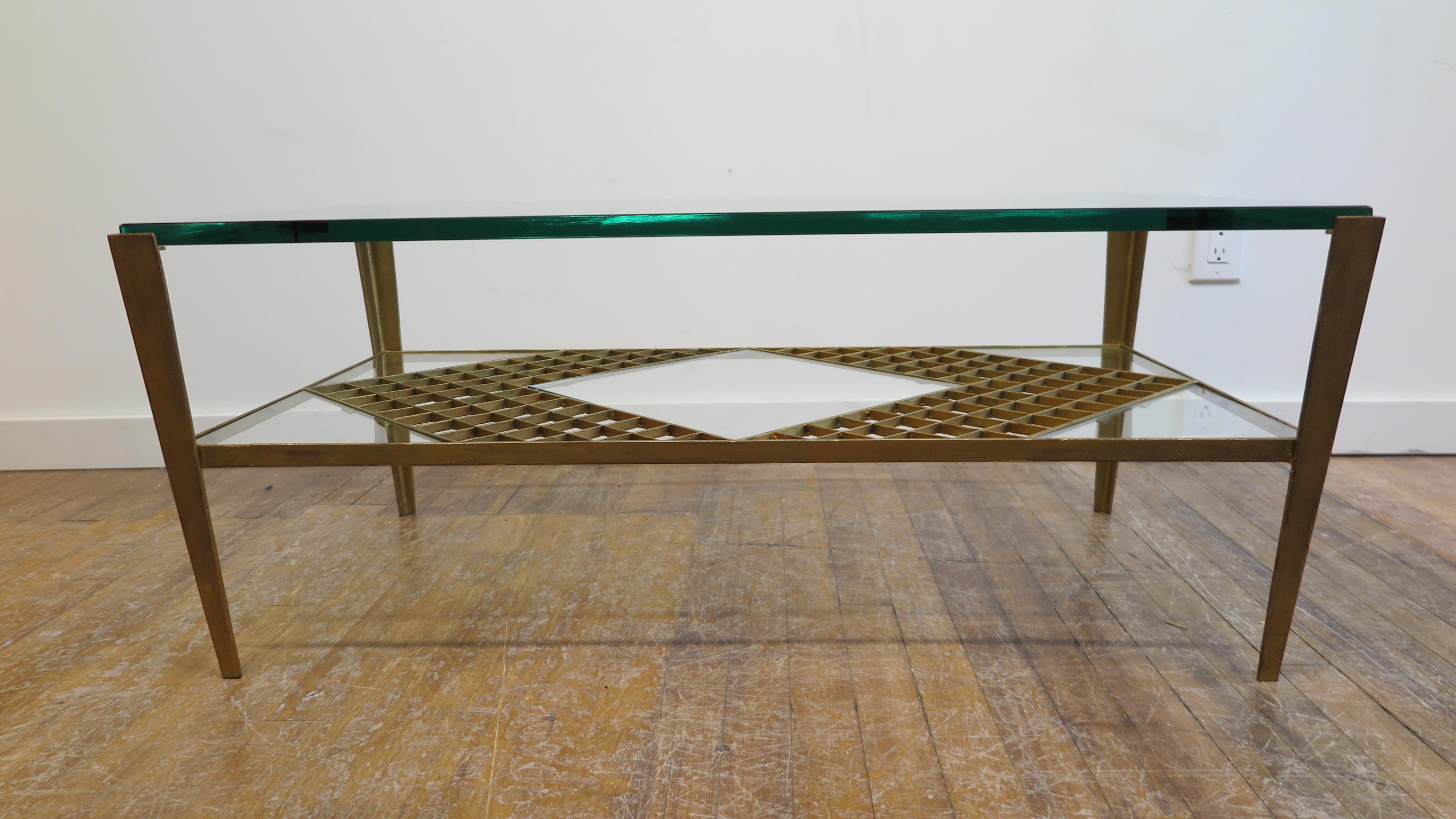 French midcentury glass cocktail table. Gilded Iron frame with inward splayed tapered legs and geometric design to the shelf having five glass inserts. This table is very striking at any angle. Very good condition.