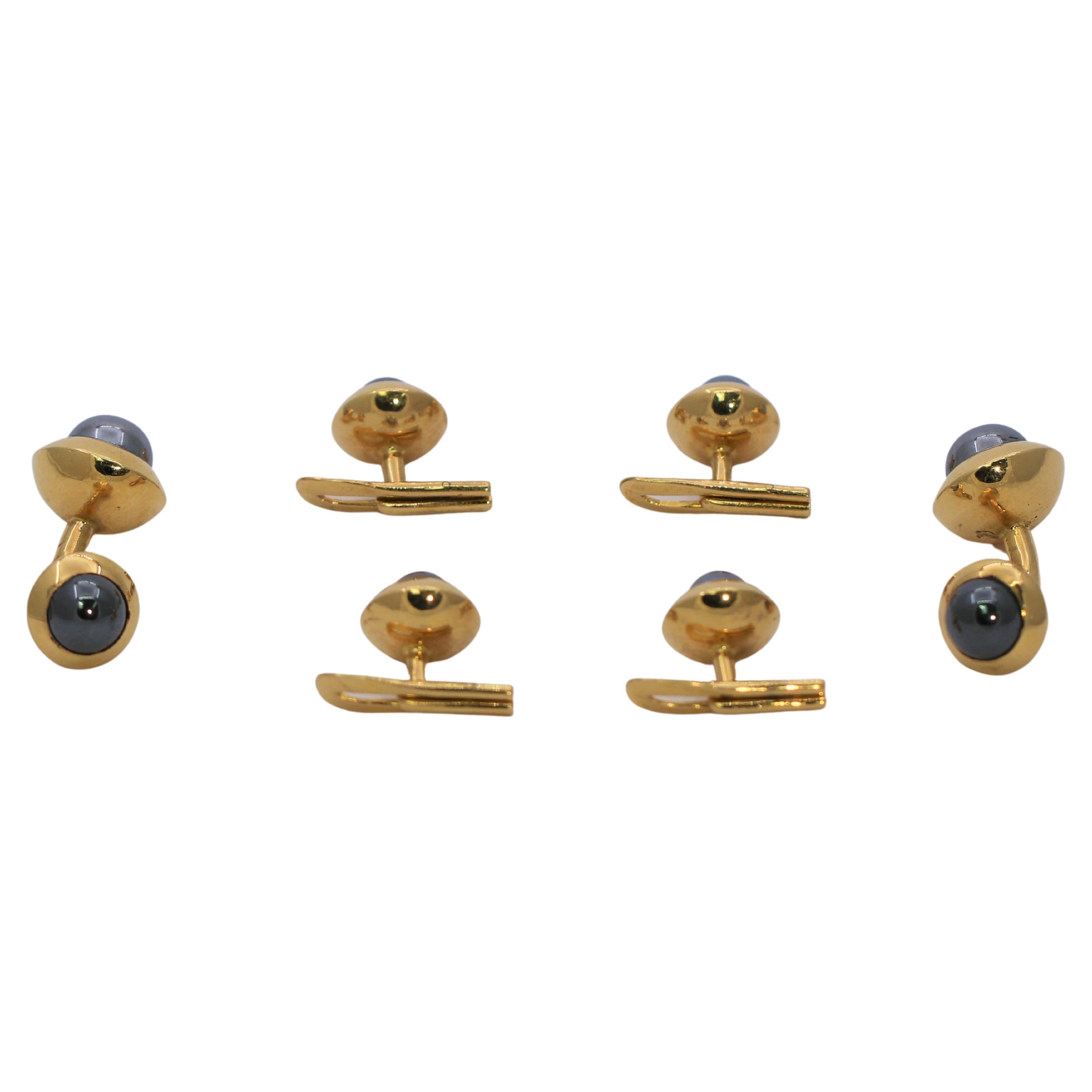 This simple but very chic 18k yellow gold French four button stud set is designed with one polished hematite bead surrounded by a wide bezel of gold on every piece. The beads measure from eight millimeters at the front of the cuff links, and 6.5
