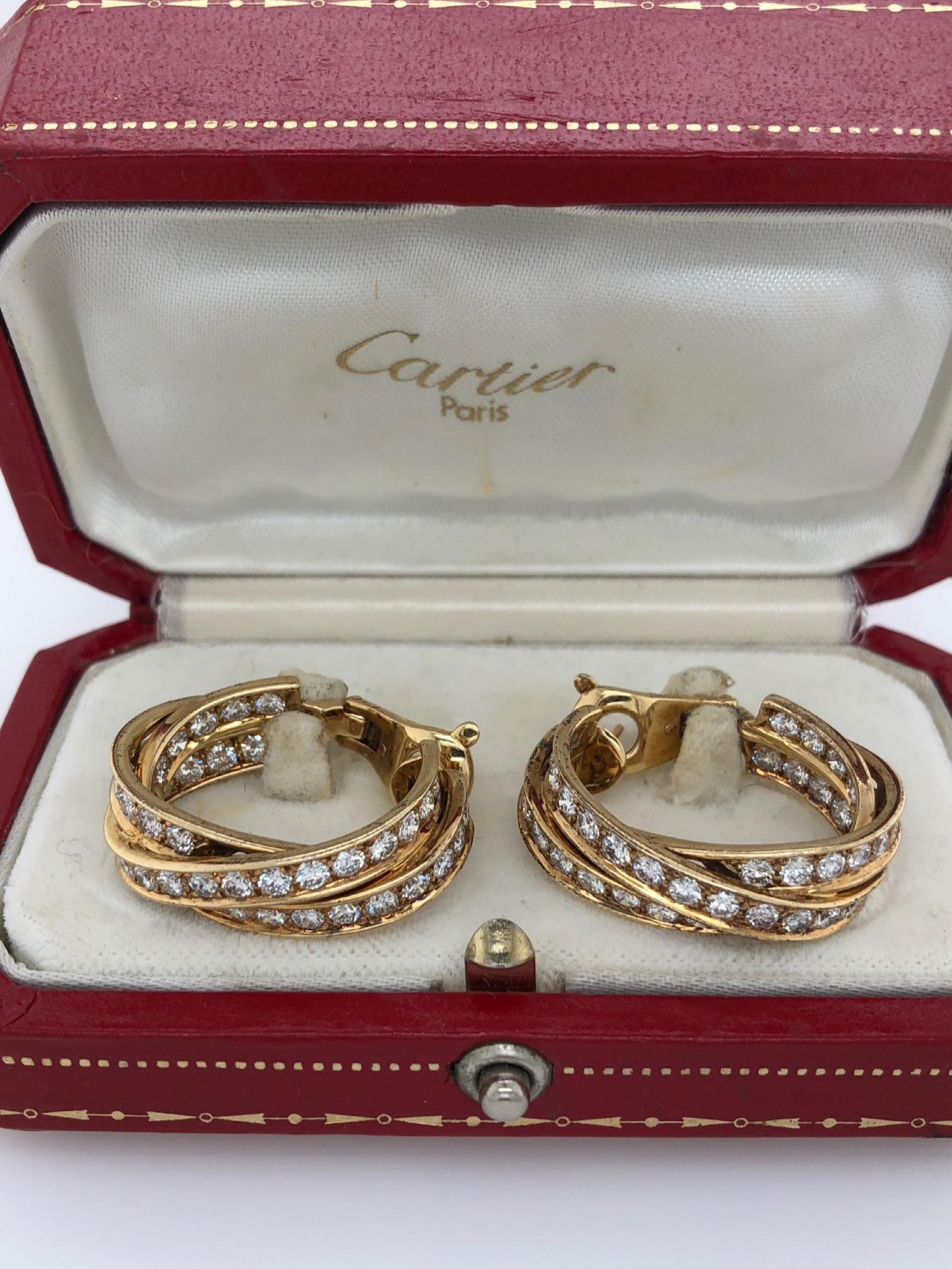 A pair of French1 8 karat gold earrings with diamond by Cartier. The three interlocking trinity bands create a dynamic hoop earring that collectively have 82 diamonds with an approximate total weight of 5.76 carats. Replete with its original box. 