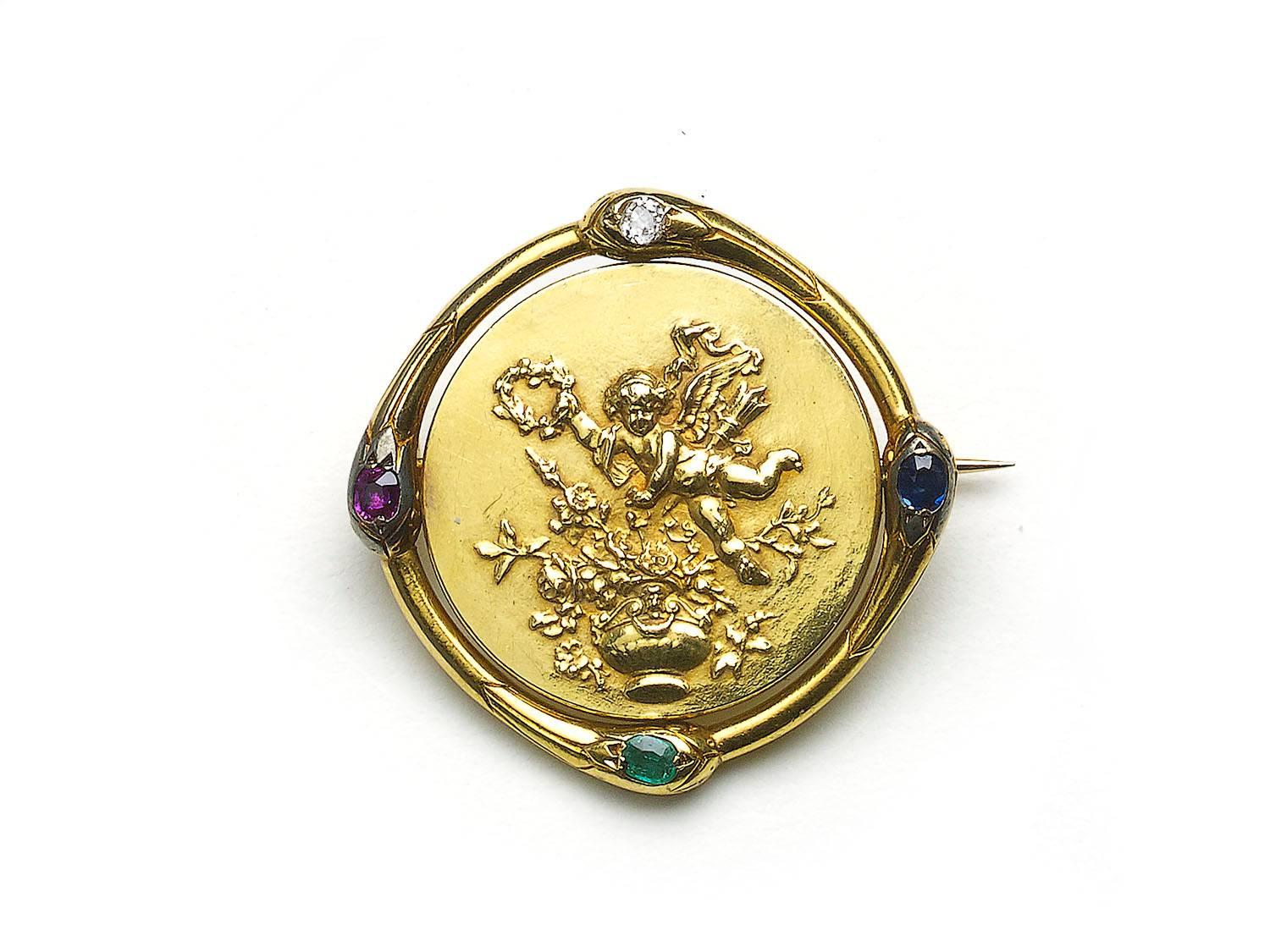 A French gold brooch, central spinning disc depicting a cherub with a lute, holding onto surrounding flowers, with a cherub holding a wreath to the reverse, surrounded by four snakes biting each other's tail, each set with a gemstone in it's head,