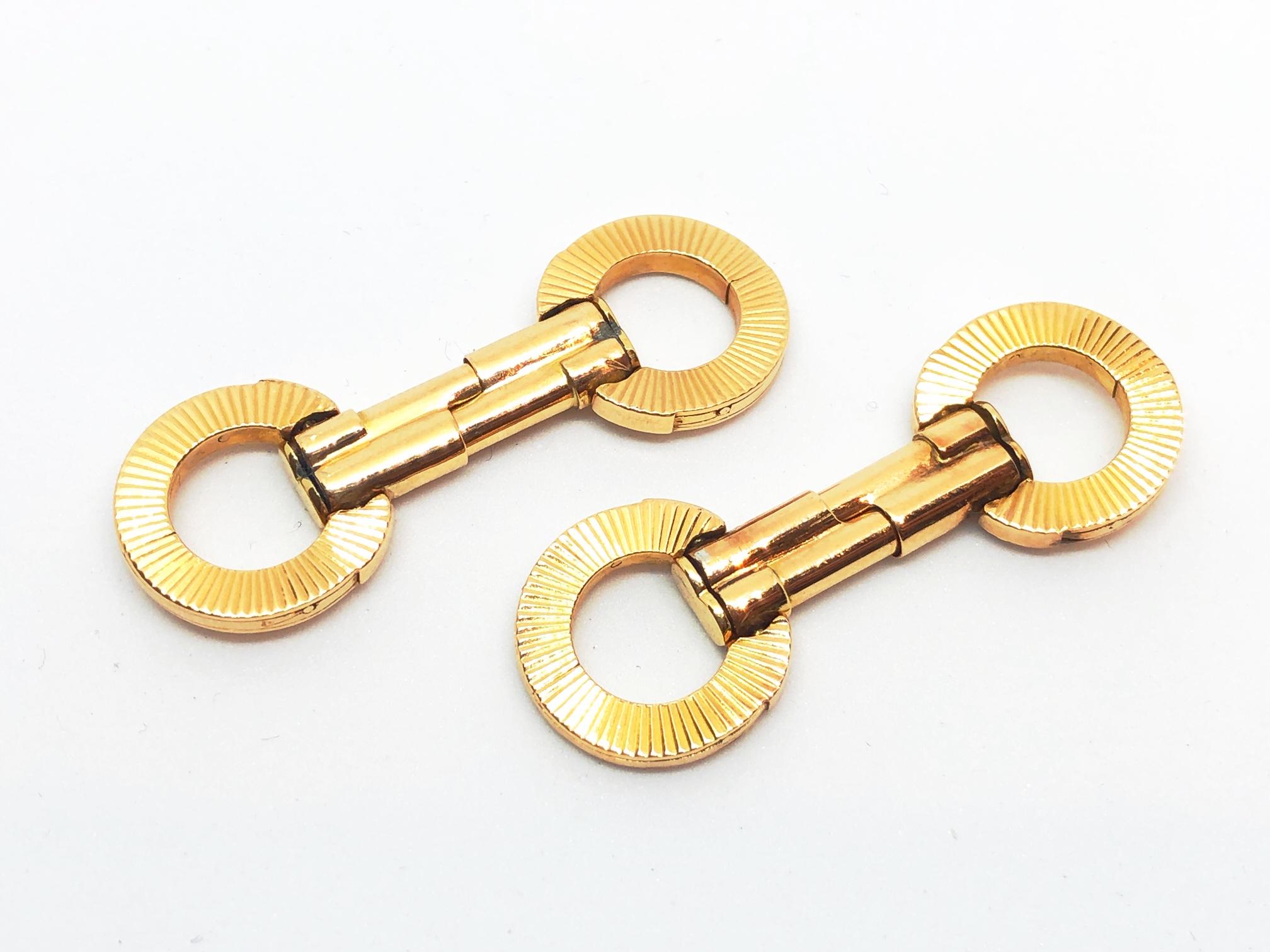 A pair of French engraved gold cufflinks, with folding, circle stirrup style ends, with radiating reeded engraving, with sprung double bar fittings, with French eagle head marks for 18ct gold, circa 1950.
Length approximately 43mm, when unfolded, 14