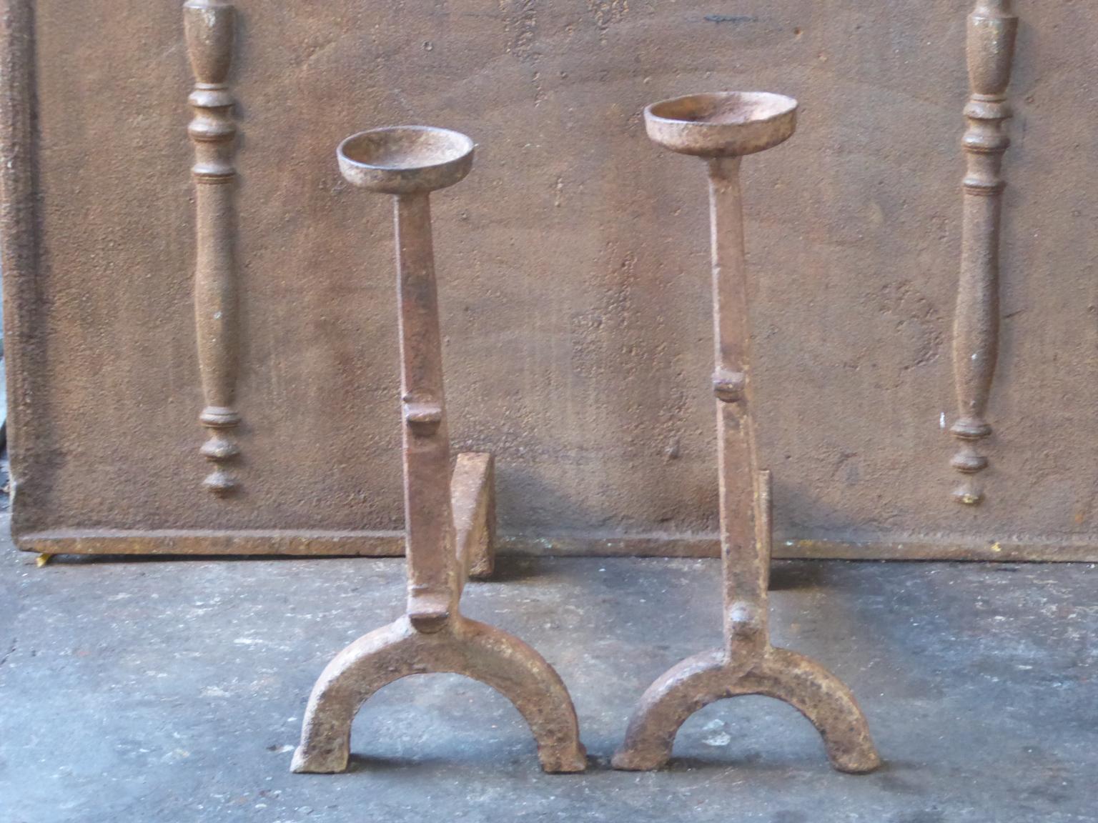 17th-18th century French andirons made of cast iron. The style of the andirons is Gothic. The andirons have spit hooks to grill food and a cup to keep drinks warm. They are in a good condition.