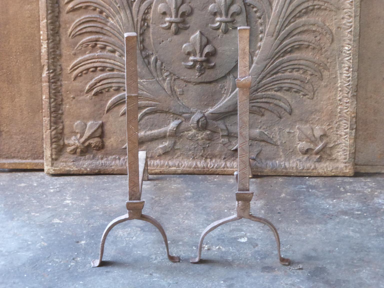 17th-18th century French andirons made of wrought iron. The style of the andirons is Gothic. The andirons have spit hooks to grill food. They are in a good condition.