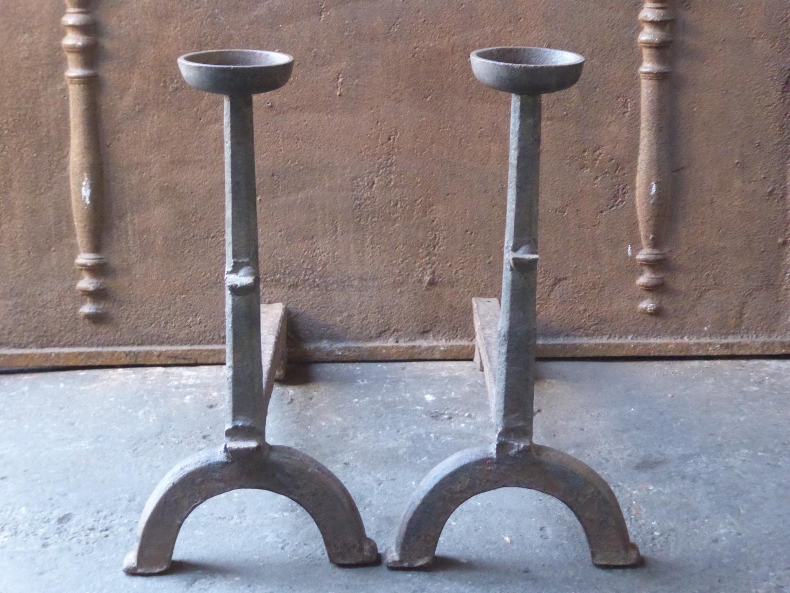 17th-18th century French andirons made of cast iron. The style of the andirons is Gothic. The andirons have spit hooks to grill food and a cup to keep drinks warm. They are in a good condition. 

These French andirons are called 'landiers' in