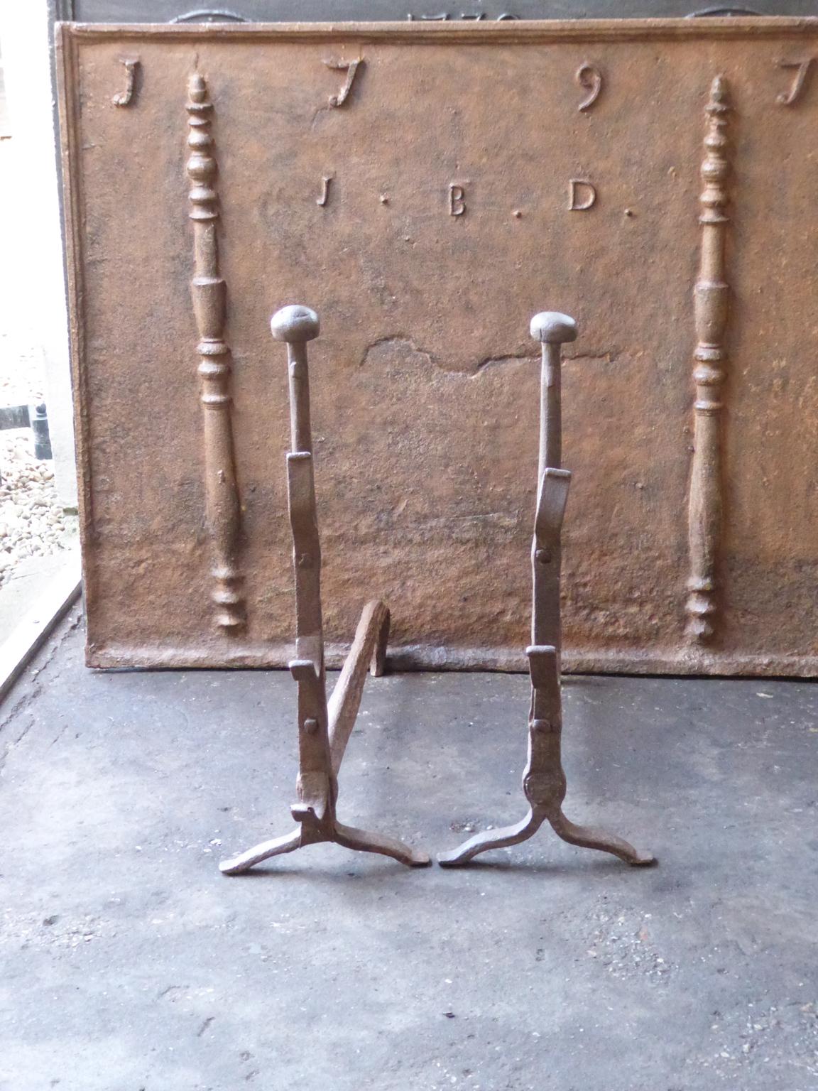 17th-18th century French andirons made of wrought iron. The style of the andirons is Gothic. The andirons have spit hooks to grill food. They are in a good condition.