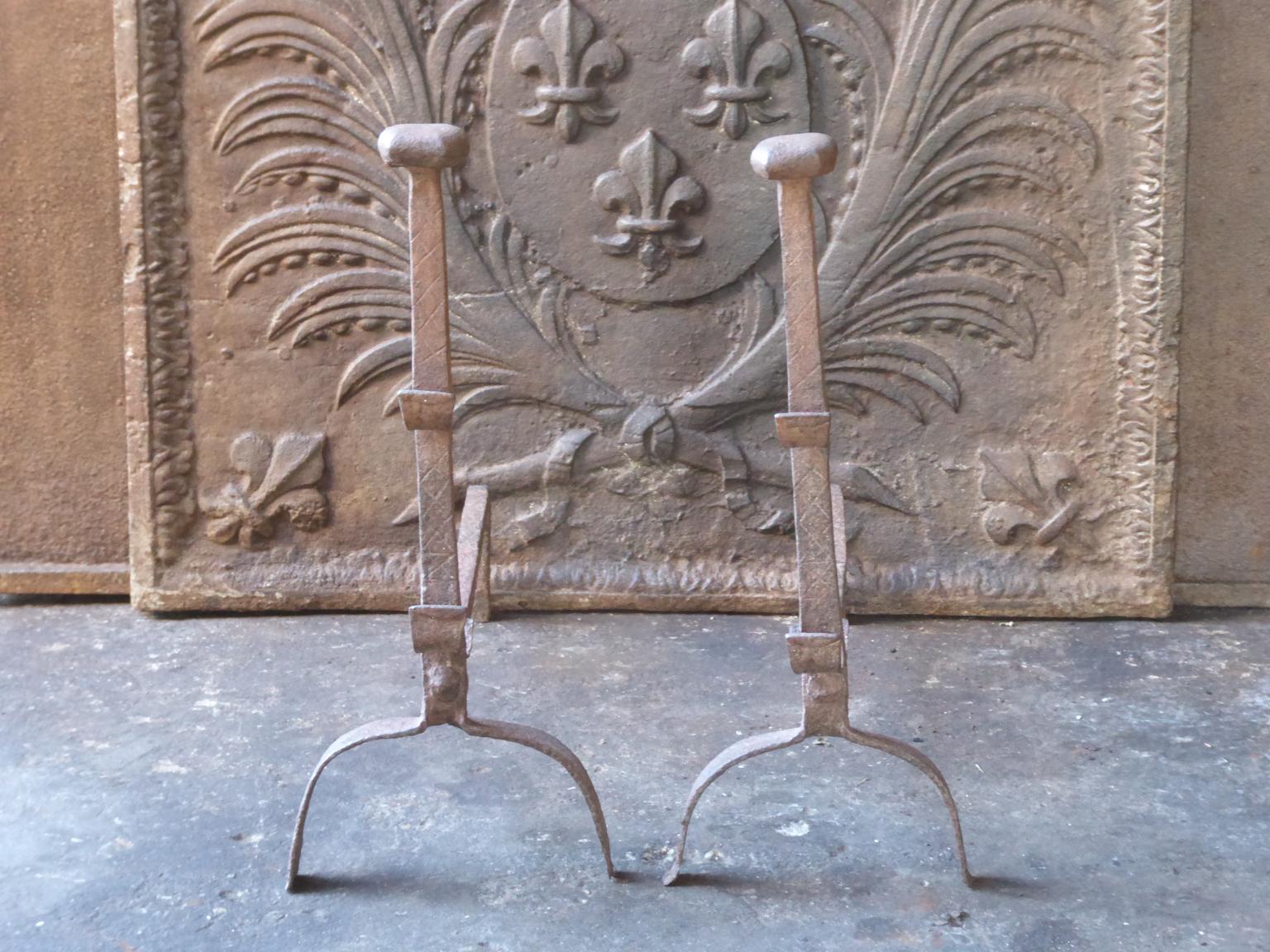 17th century French andirons made of wrought iron. The style of the andirons is Gothic. The andirons have spit hooks to grill food. They are in a good condition.