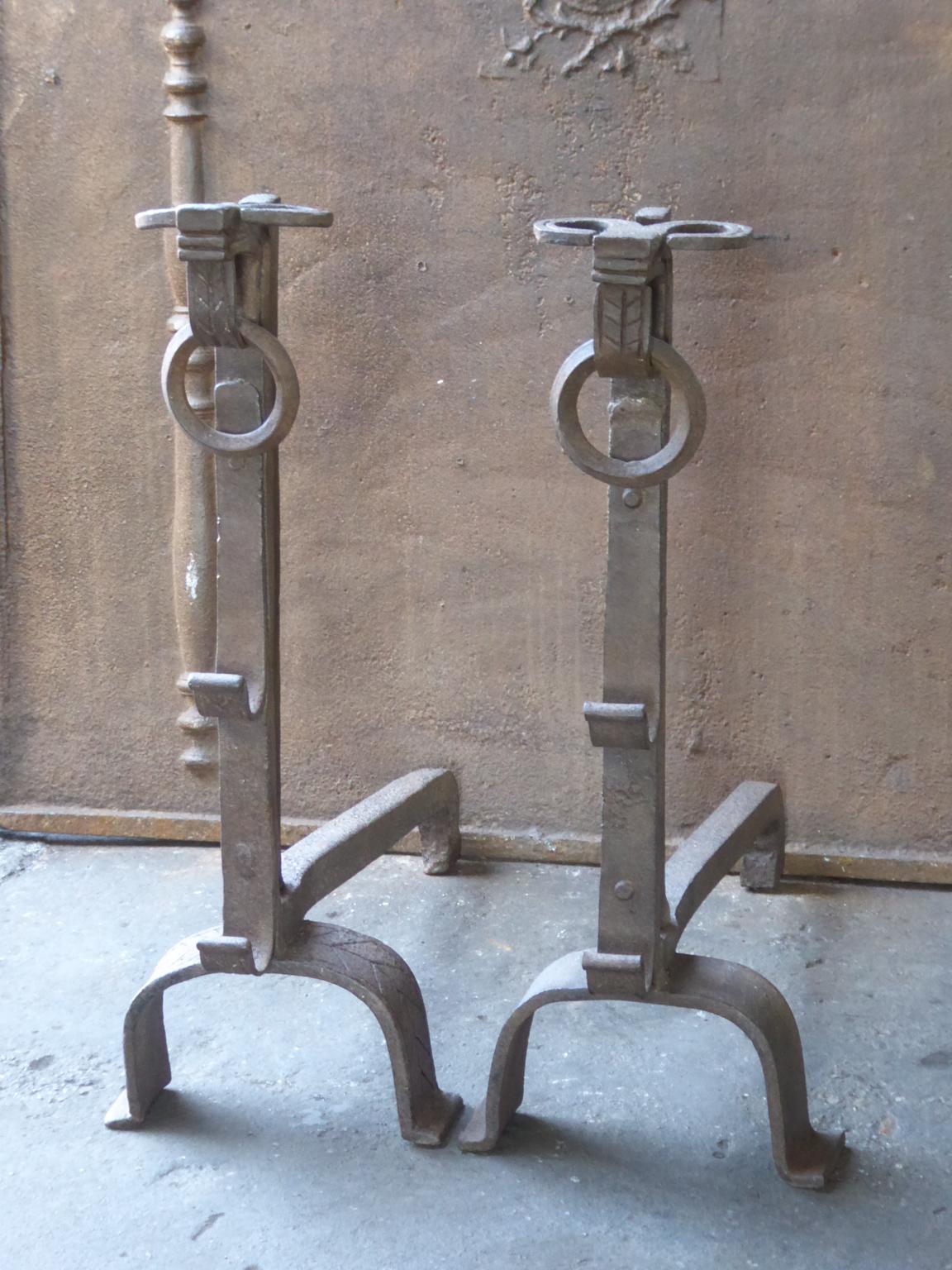 17th century French andirons made of wrought iron. The style of the andirons is Gothic. The tops of the andirons have the shape of a bulls head. The andirons have spit hooks to grill food. They are in a good condition.
