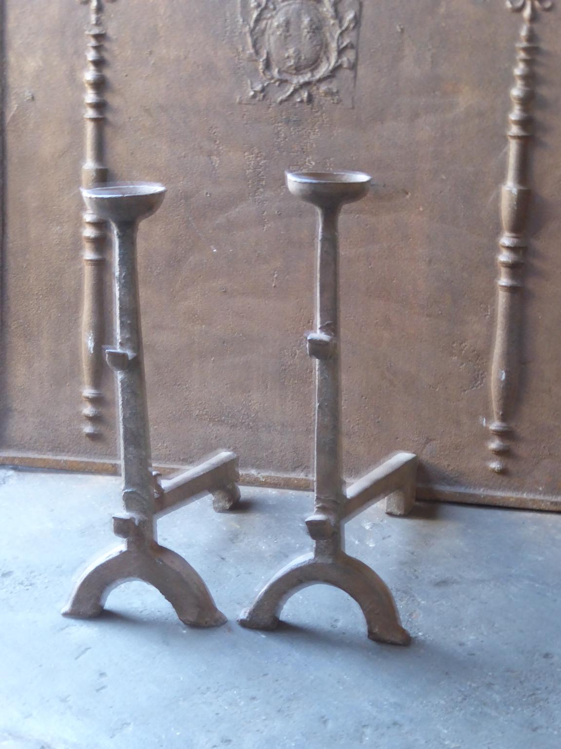 17th century French andirons made of cast iron. The style of the andirons is Gothic. The andirons have spit hooks to grill food and a cup to keep drinks warm. They are in a good condition.