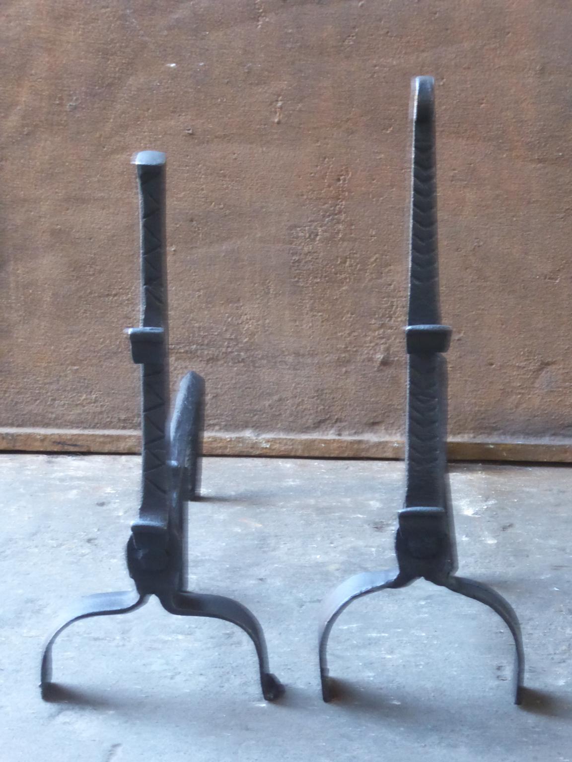 17th century French andirons made of wrought iron. The style of the andirons is Gothic. The andirons have spit hooks to grill food. They are in a good condition.