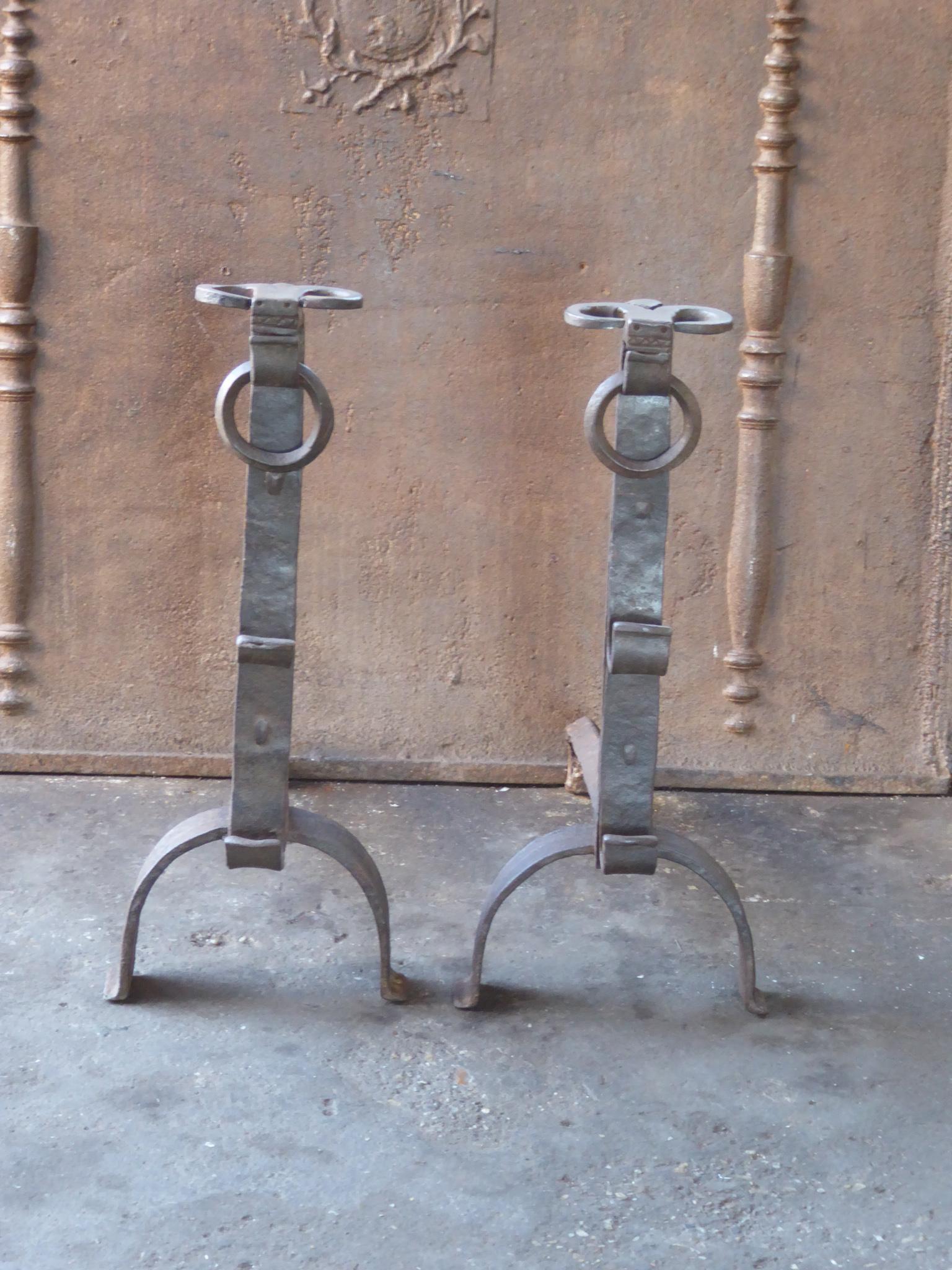 Hand forged 17th century French andirons made of wrought iron. The style of the andirons is Gothic. The tops of the andirons have the shape of a bulls head. The andirons have spit hooks to grill food. They are in a good condition.