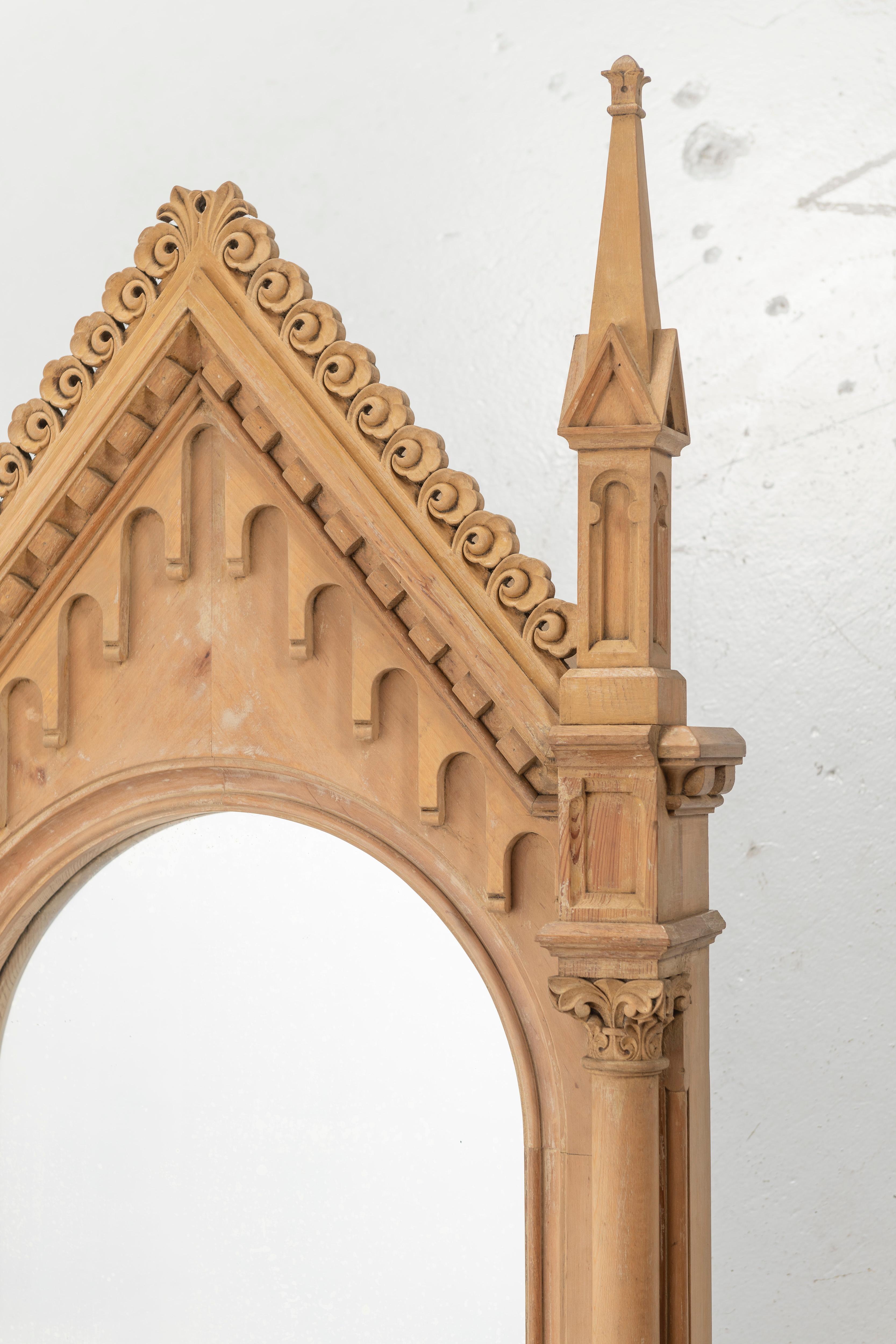 This antique carved pine gothic frame with mirror in very good condition. The 
apex pediment with carved details is flanked by spired finials. The mirror is set within arched frames with spiral columns.
