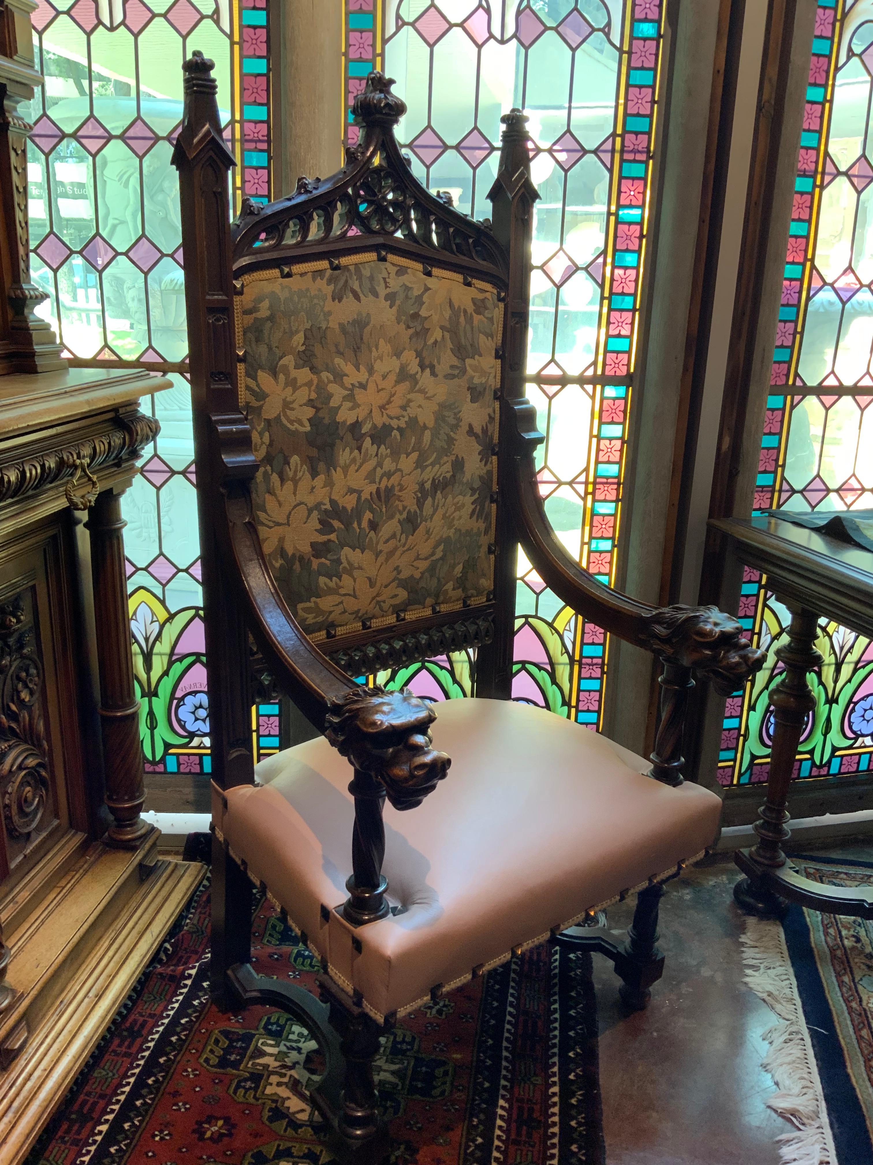 Tall carved chair in the Gothic style. 19 th c. With a leather seat and tapestry 
Upholstered back. The arms in a Griffin carved head.