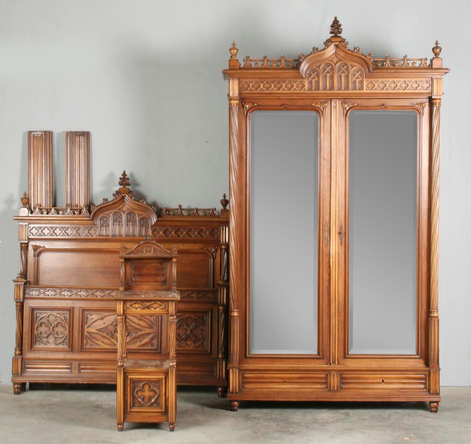3-Piece bedroom set from France, carved walnut in Gothic style. 
The wardrobe cabinet has mirrors in the doors. 
Size of the wardrobe: 268 cm tall, 156 cm wide and 55 cm deep. 
The top of the wardrobe has a few pieces missing on right, see picture