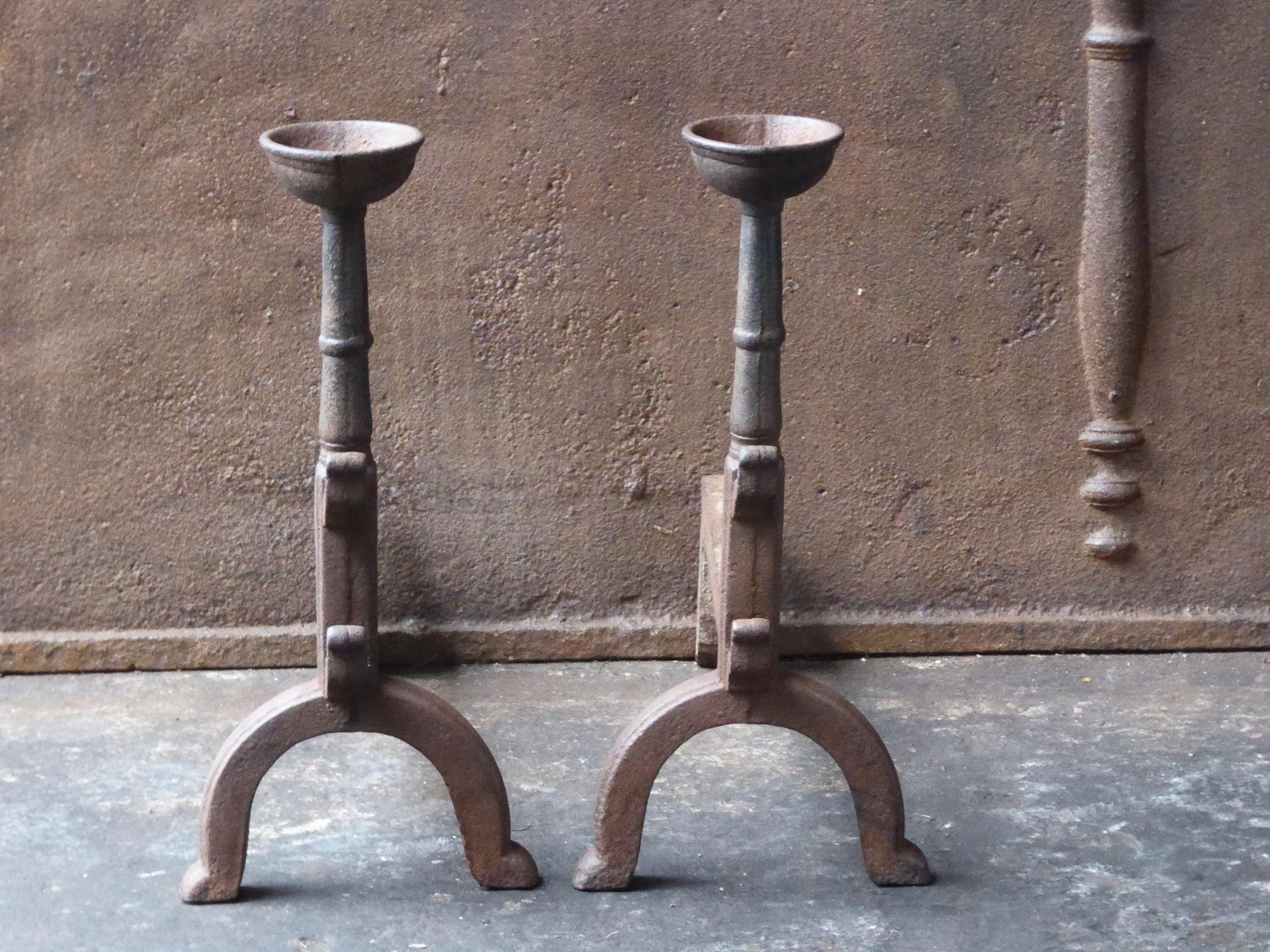 French Gothic style fire dogs made of cast iron. With spit hooks to grill food and a cup to keep drinks or soup warm. This type of andirons are also called cupdogs.

We have a unique and specialized collection of antique and used fireplace