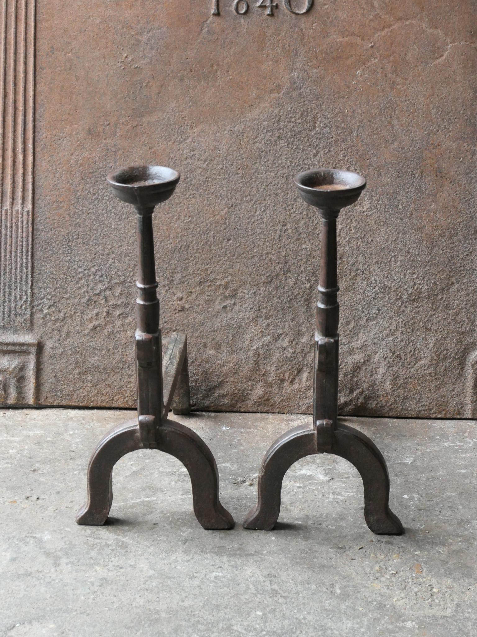 French Gothic style fire dogs made of cast iron. With spit hooks to grill food and a cup to keep drinks or soup warm. This type of andirons are also called cupdogs.

We have a unique and specialized collection of antique and used fireplace