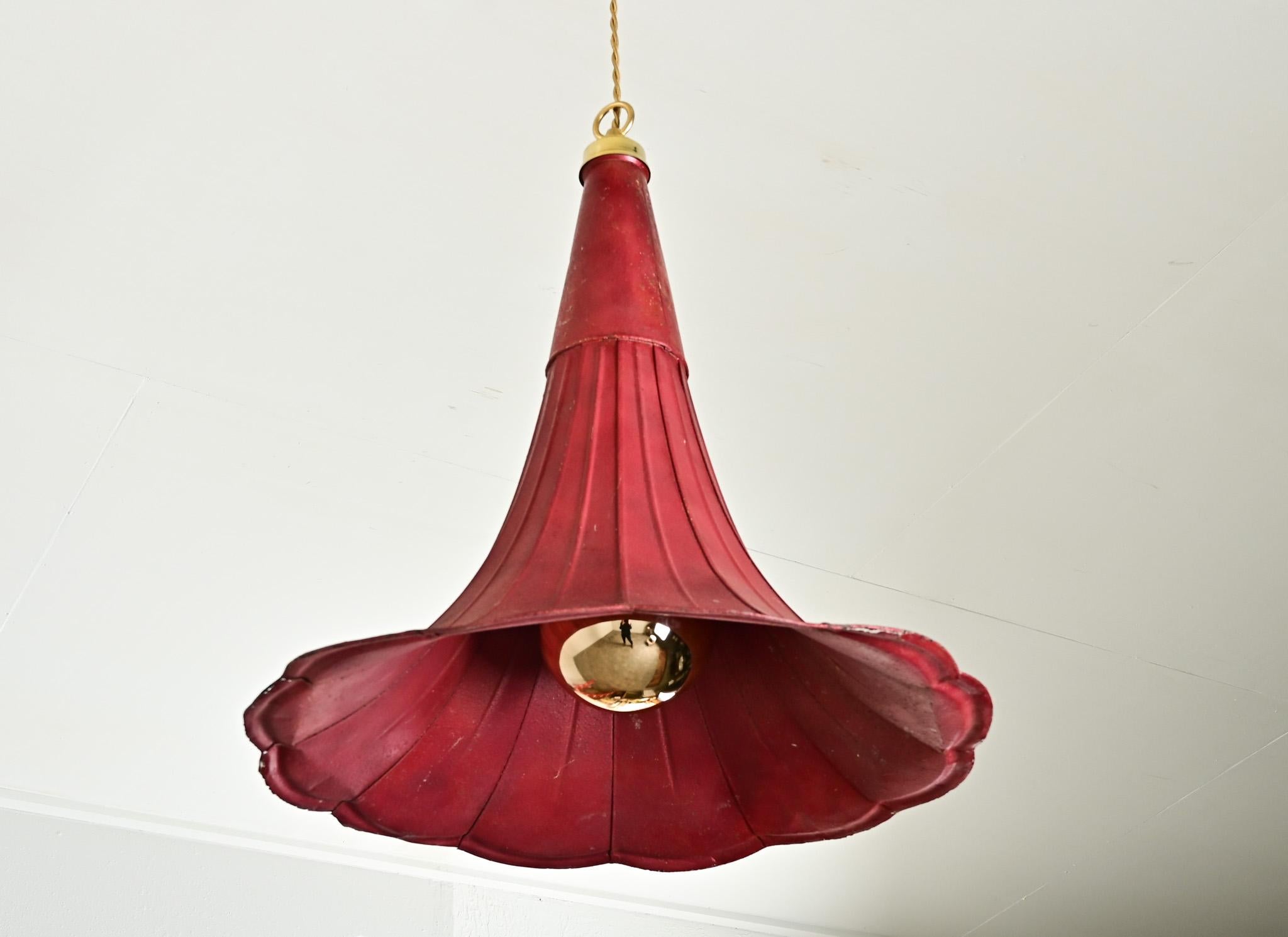 A very creative repurposing of an antique phonograph horn, this French pendant light fixture is an inverted speaker, now wired to hold a single bulb. The diffuser of the lamp is an eyecatching red tole, the metal cone flaring out to a scalloped edge