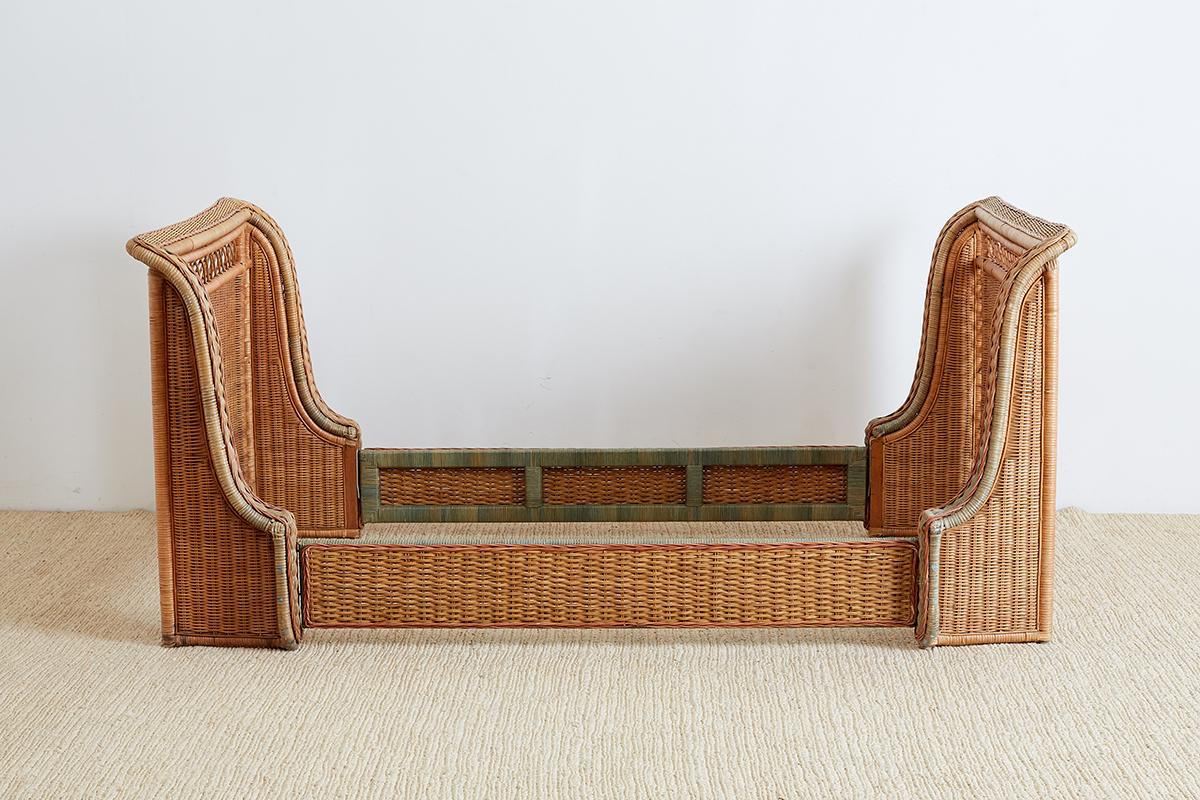 Stylish French Art Deco style sleigh bed constructed from wicker and rattan. Attributed to Grange featuring decorative patterns and faded trim in red and green. Inside measures 42 wide by 78 inches long which fits a twin mattress and box spring.