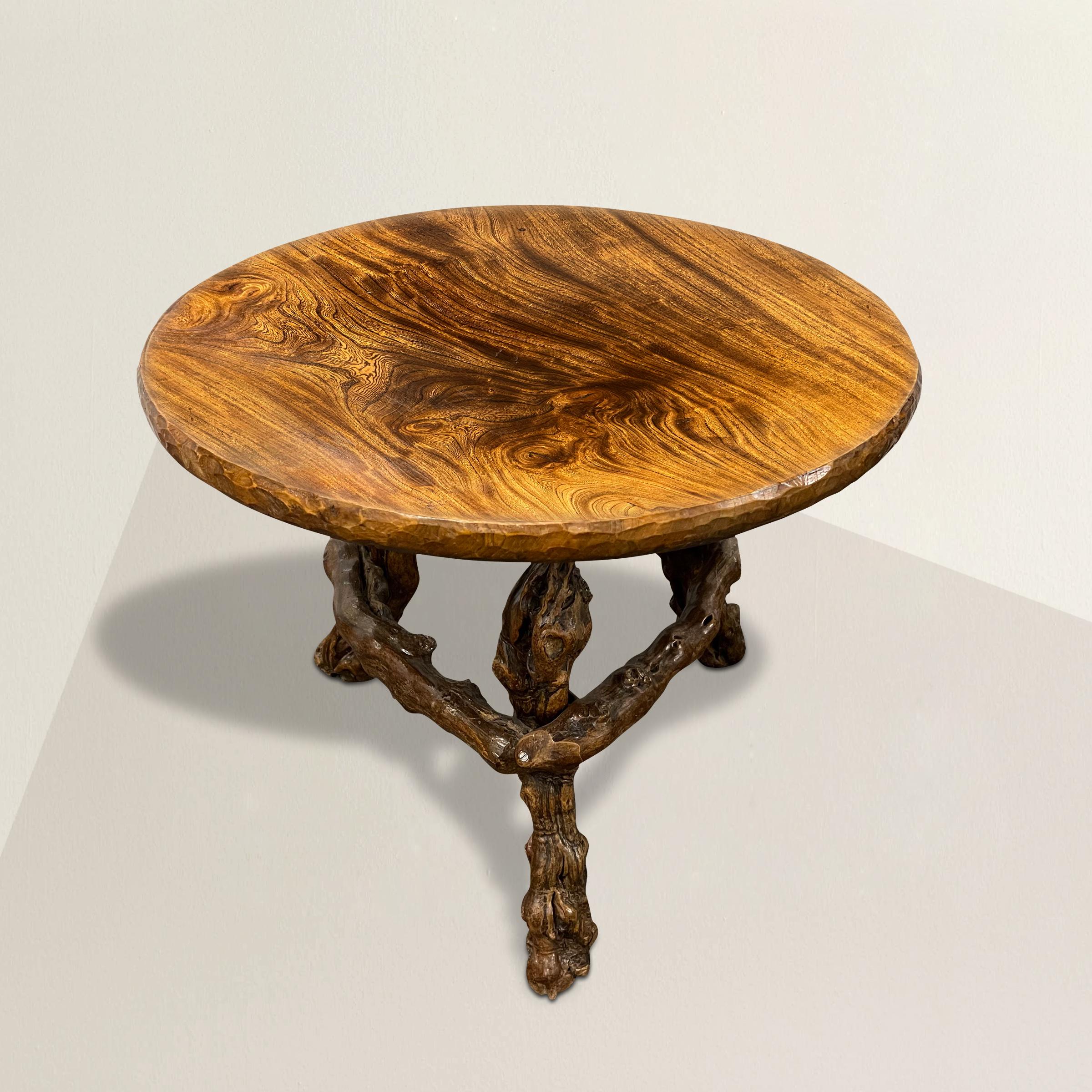 A wonderfully whimsical mid-20th century French table with a thick mahogany top with chip-carved edge detail, and supported by three burled grapevine legs connected with stretchers. The perfect side table next to a sofa or your favorite armchair, or