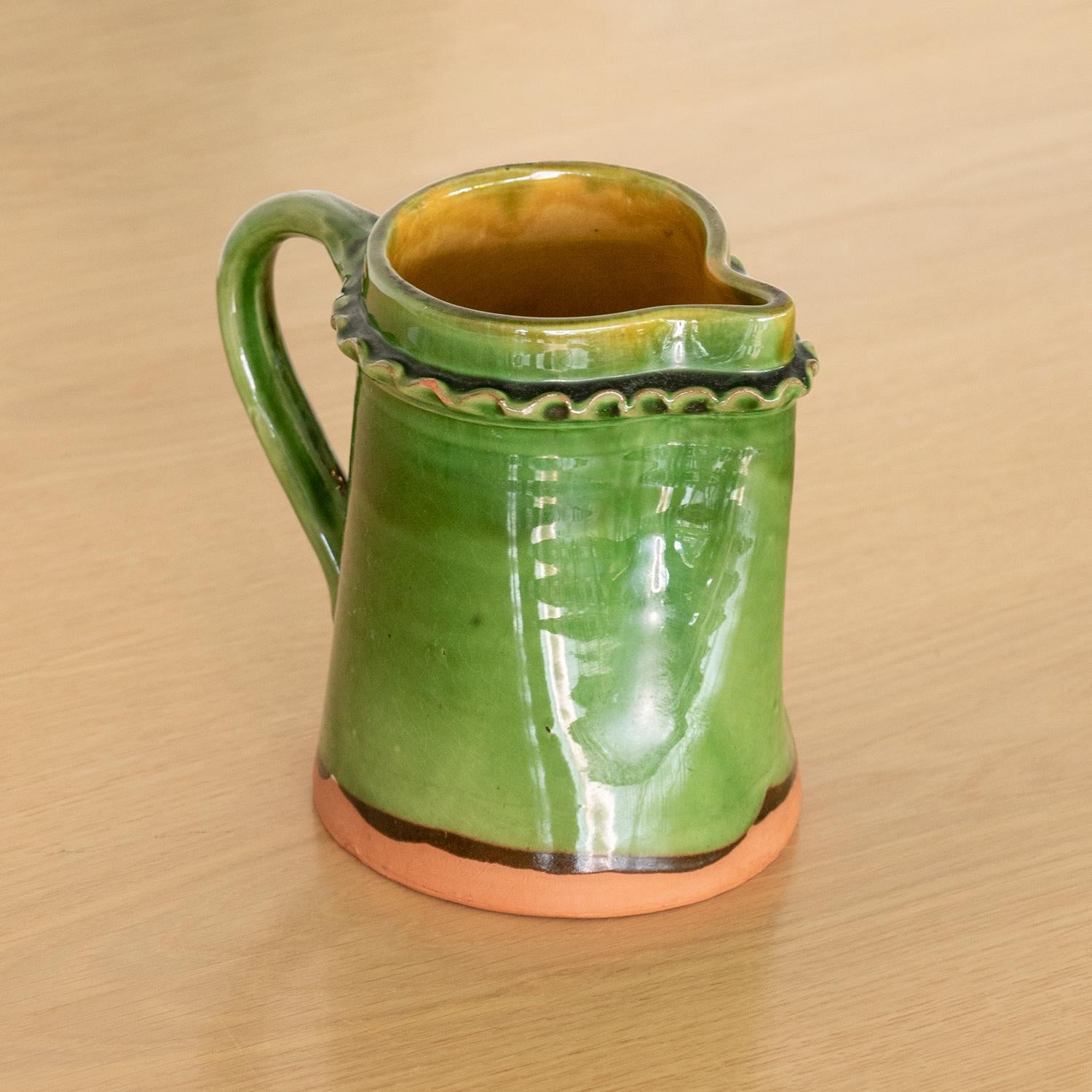 Beautiful handmade ceramic pitcher from France. Dark green glazed ceramic pitcher with handle and scalloped detail on rim. Stamped on side.