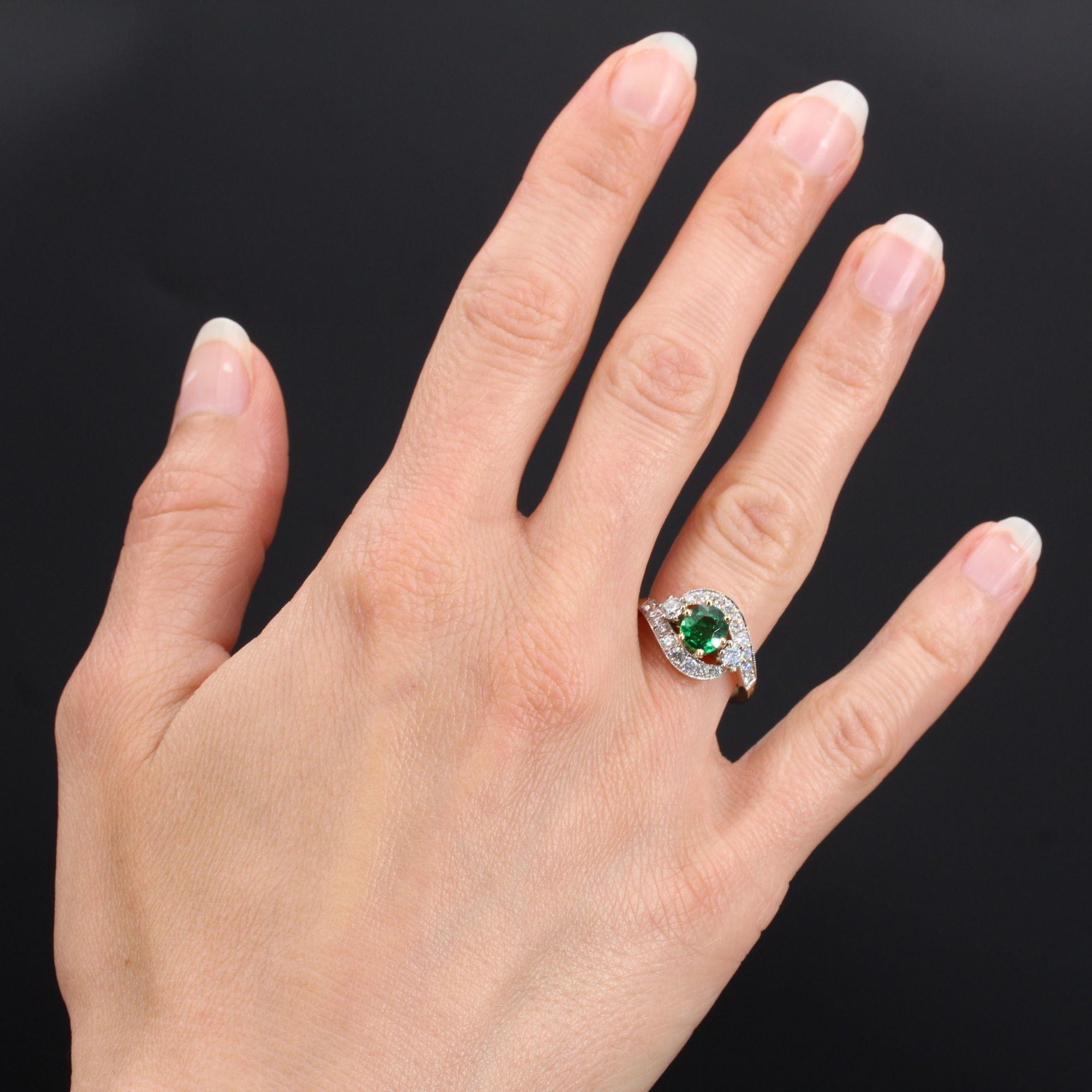 Ring in 18 karat yellow gold, eagle head hallmark and platinum, dog head hallmark.
Asymmetrical, this magnificent ring is set with a green garnet, with two modern brilliant- cut diamonds. The whole ring is bordered on both sides by lines of modern
