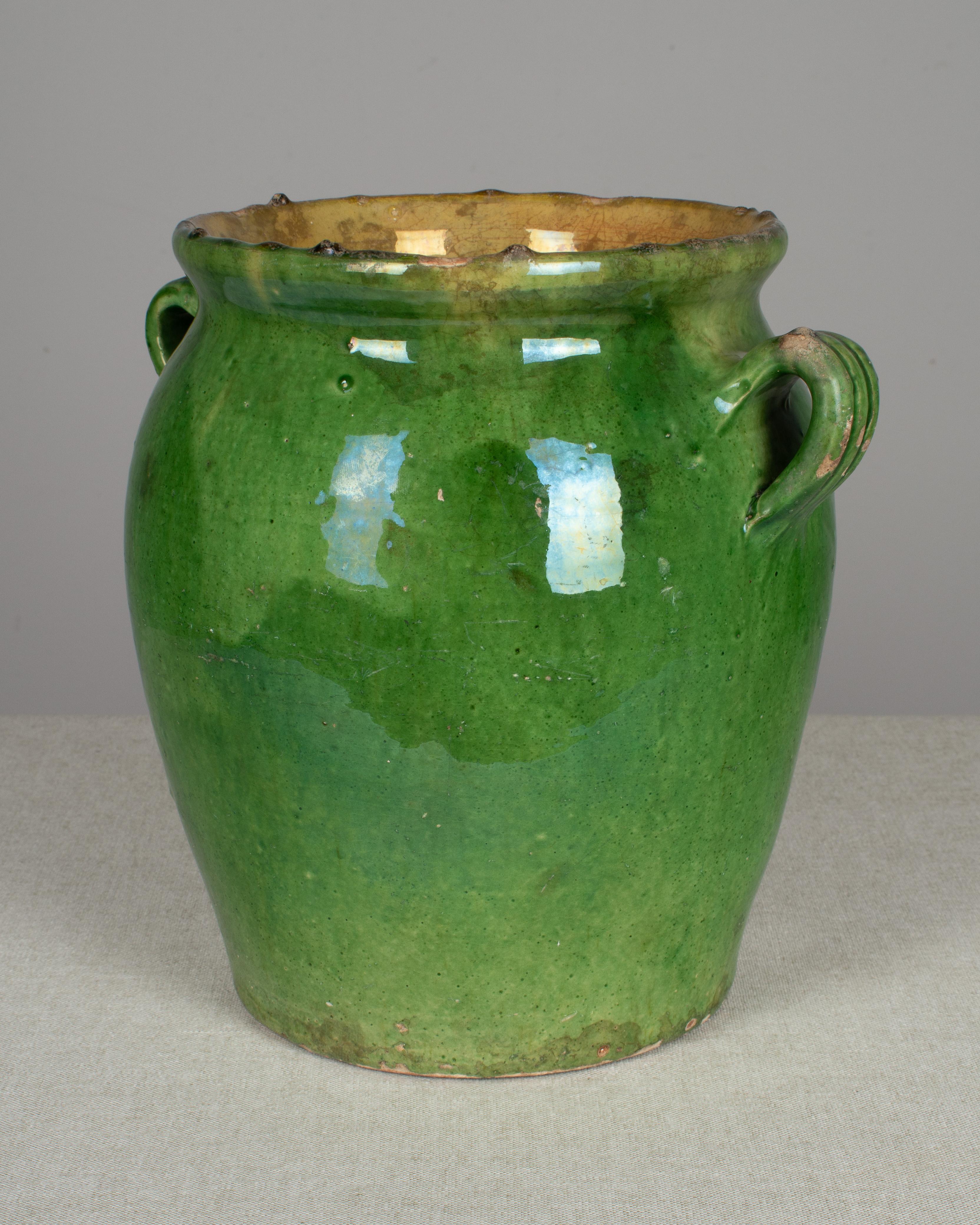 An earthenware confit pot from the Southwest of France with traditional green glaze. These ordinary earthenware vessels were once used daily in the French country home and have beautiful rustic glazes of green, ochre and terracotta. Nice decorative