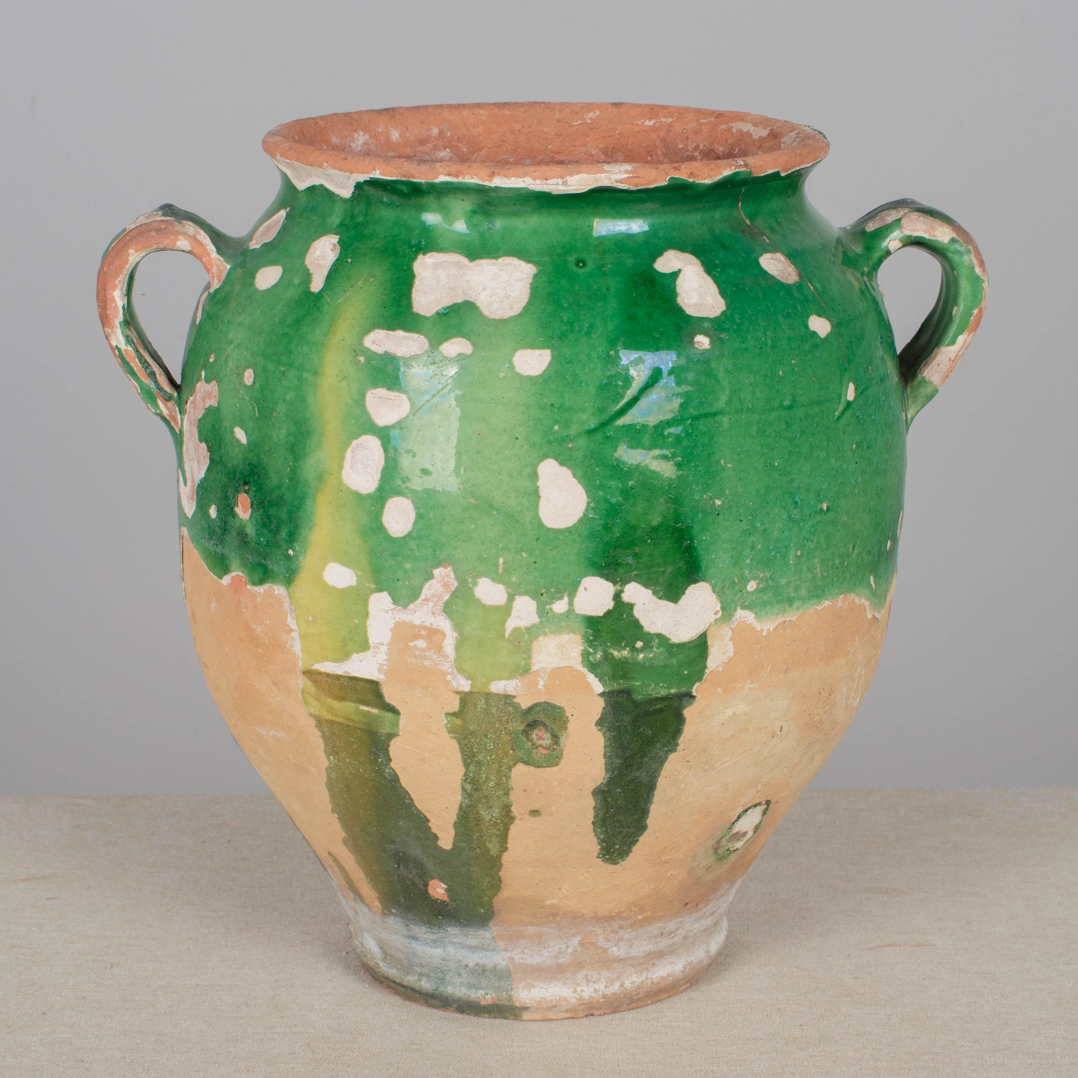 A French earthenware confit pot with traditional green glaze. These ordinary earthenware vessels were once used daily in the French country home and have beautiful rustic glazes of green, ochre and terracotta. Nice decorative elements especially
