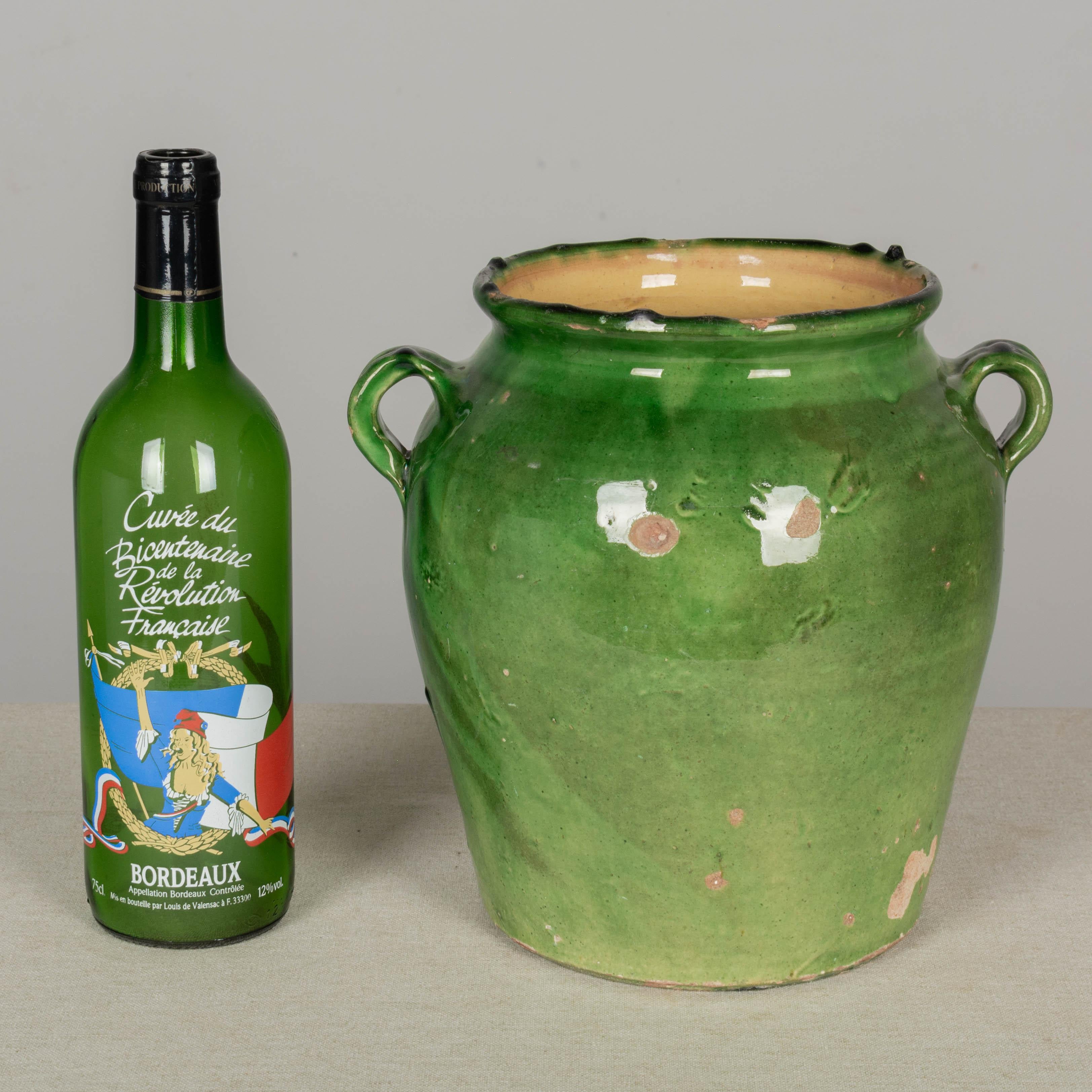 A terracotta earthenware pot from the Southwest of France with green glaze and yellow interior. Minor chips and losses to glaze. These ordinary earthenware vessels were once used daily in the French country home and have beautiful rustic glazes of
