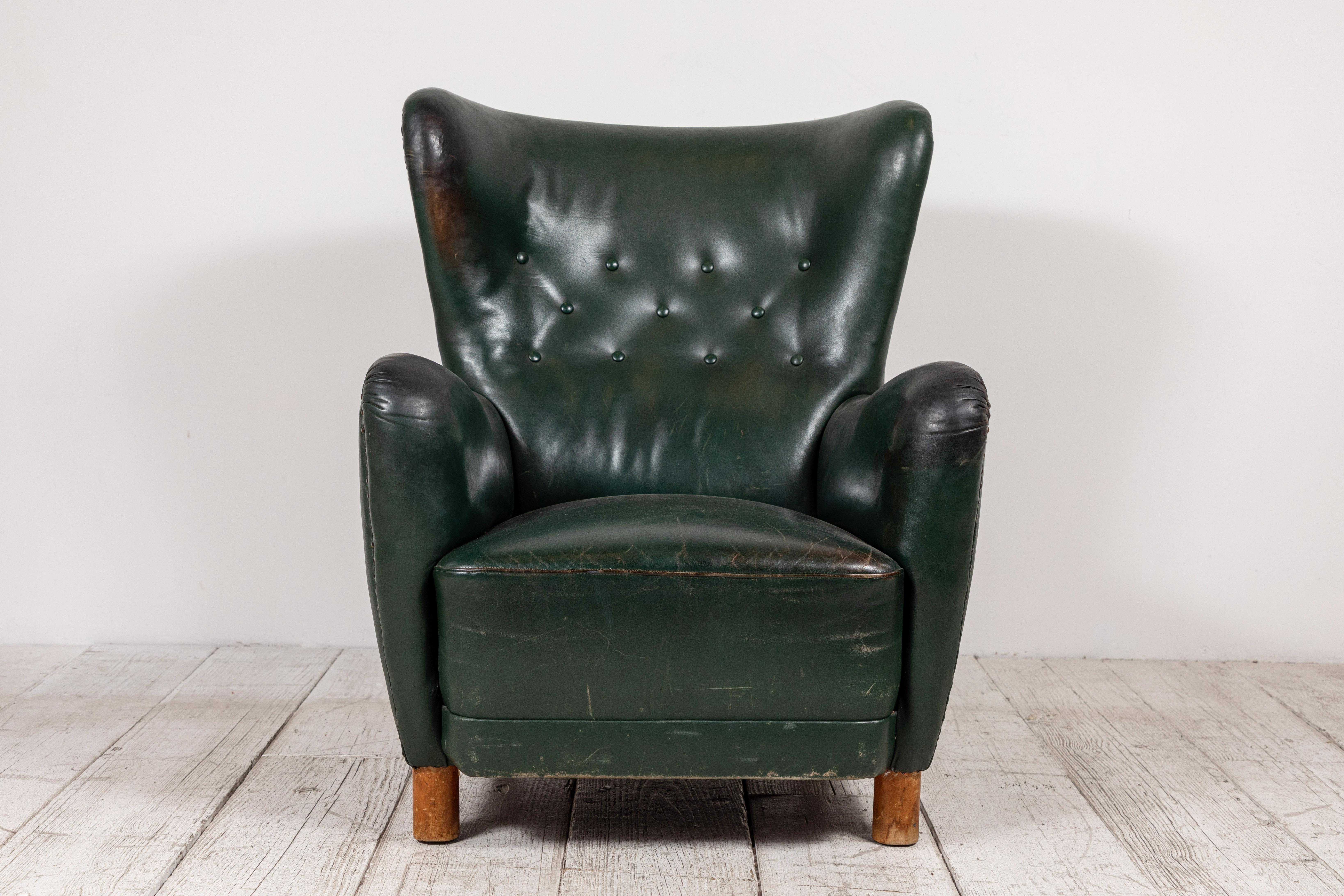 Elegant French green leather wingback chair with button details. The chair has been fully restored and it in excellent vintage condition. Legs are original which adds to the one of a kind character.