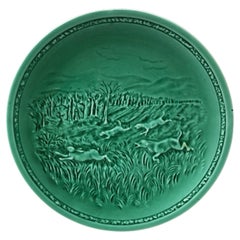 Assiette en majolique verte française représentant un harnais et un chien de chasse Sarreguemines, vers 1920