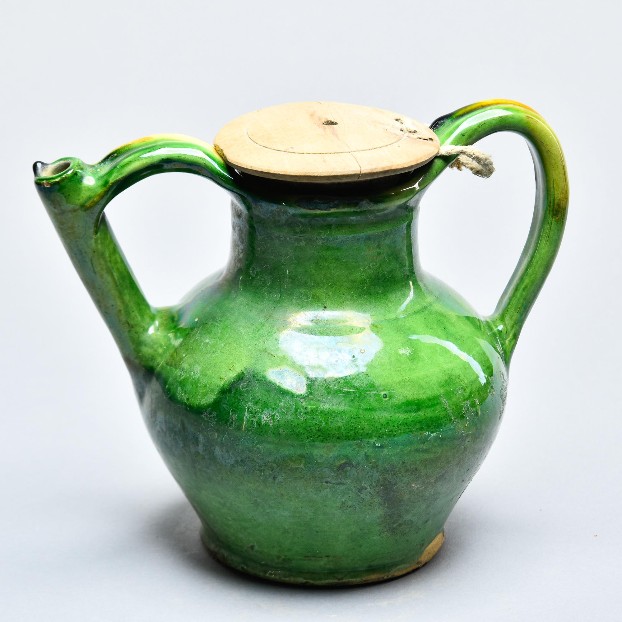 Diese grün glasierte Keramikkanne wurde in Frankreich gefunden und stammt aus der Zeit um 1910. Klassische provinzielle Amphorenform, bei der einer der Griffe eine funktionale Ausgieß- und Füllöffnung aufweist. Es ist sehr ungewöhnlich, diese Gefäße