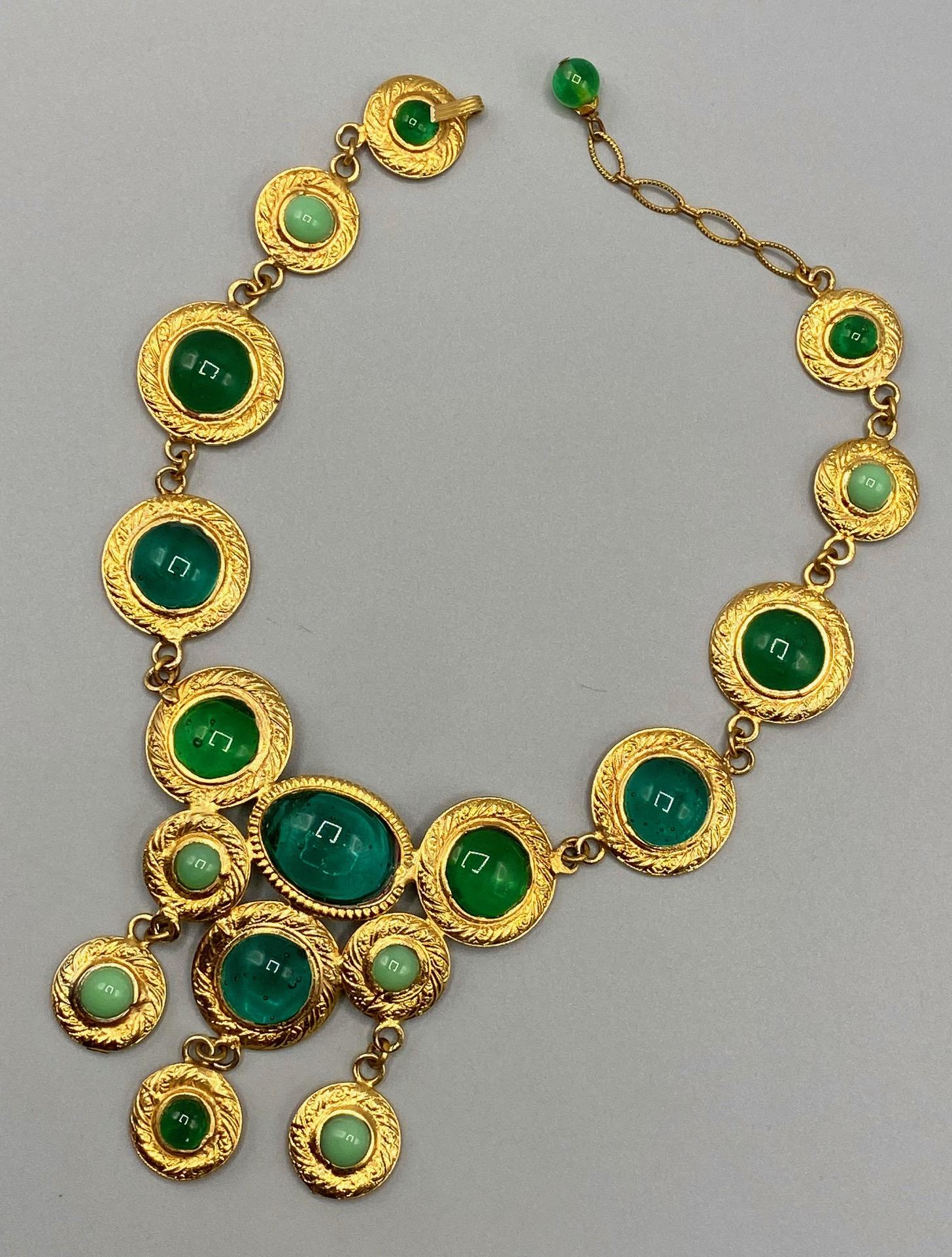 A wonderful gold tone necklace with teal, emerald green and light green poured glass bib necklace from France circa 1980. The necklace is comprised of round and oval textured gold disks with poured glass cabochons. The larger round disks are 1 inch