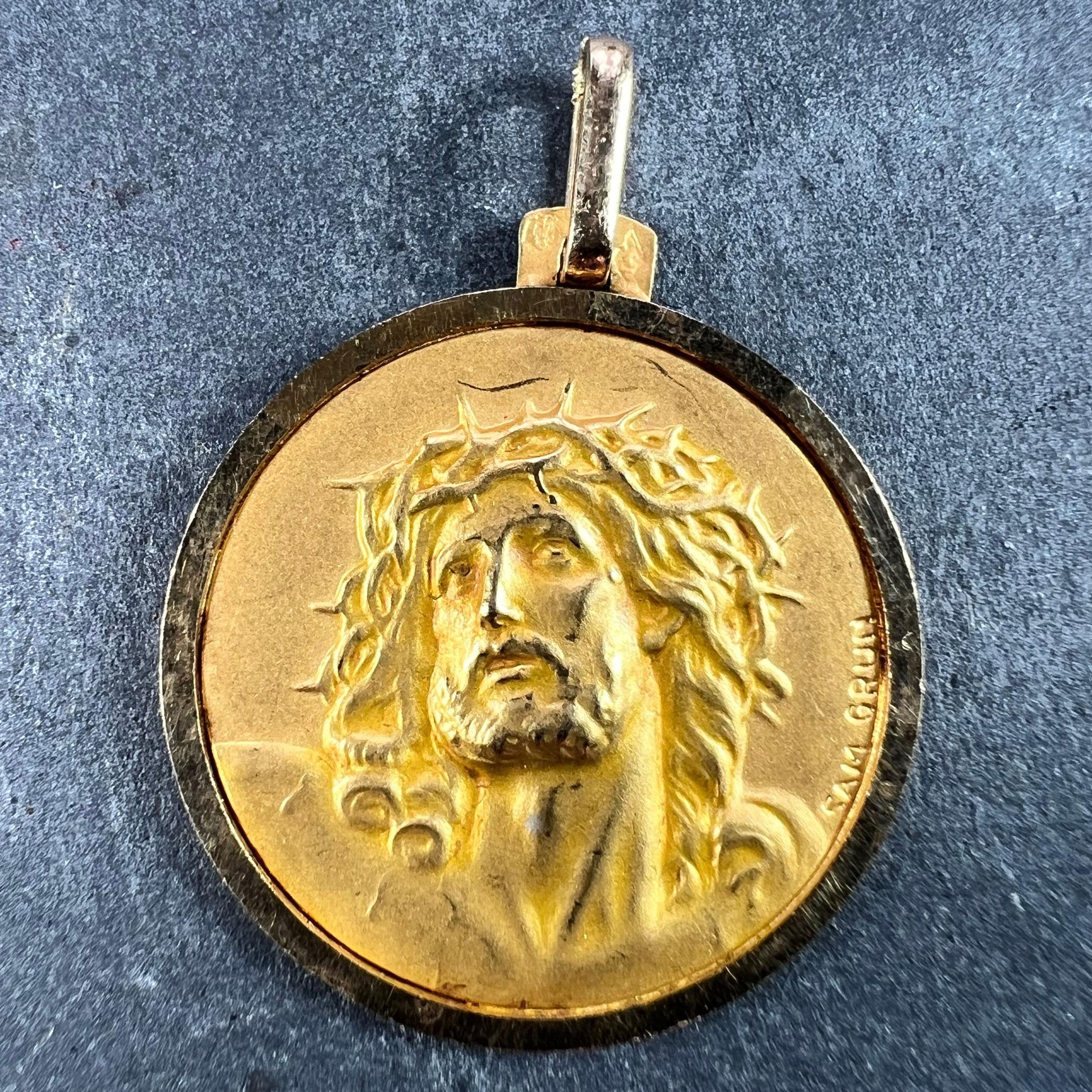 A French 18 karat (18K) yellow gold charm pendant designed as a round medal depicting Jesus Christ wearing the Crown of Thorns. Signed Sam Grün, stamped with the eagle’s head for 18 karat gold and French manufacture, along with an unknown maker's