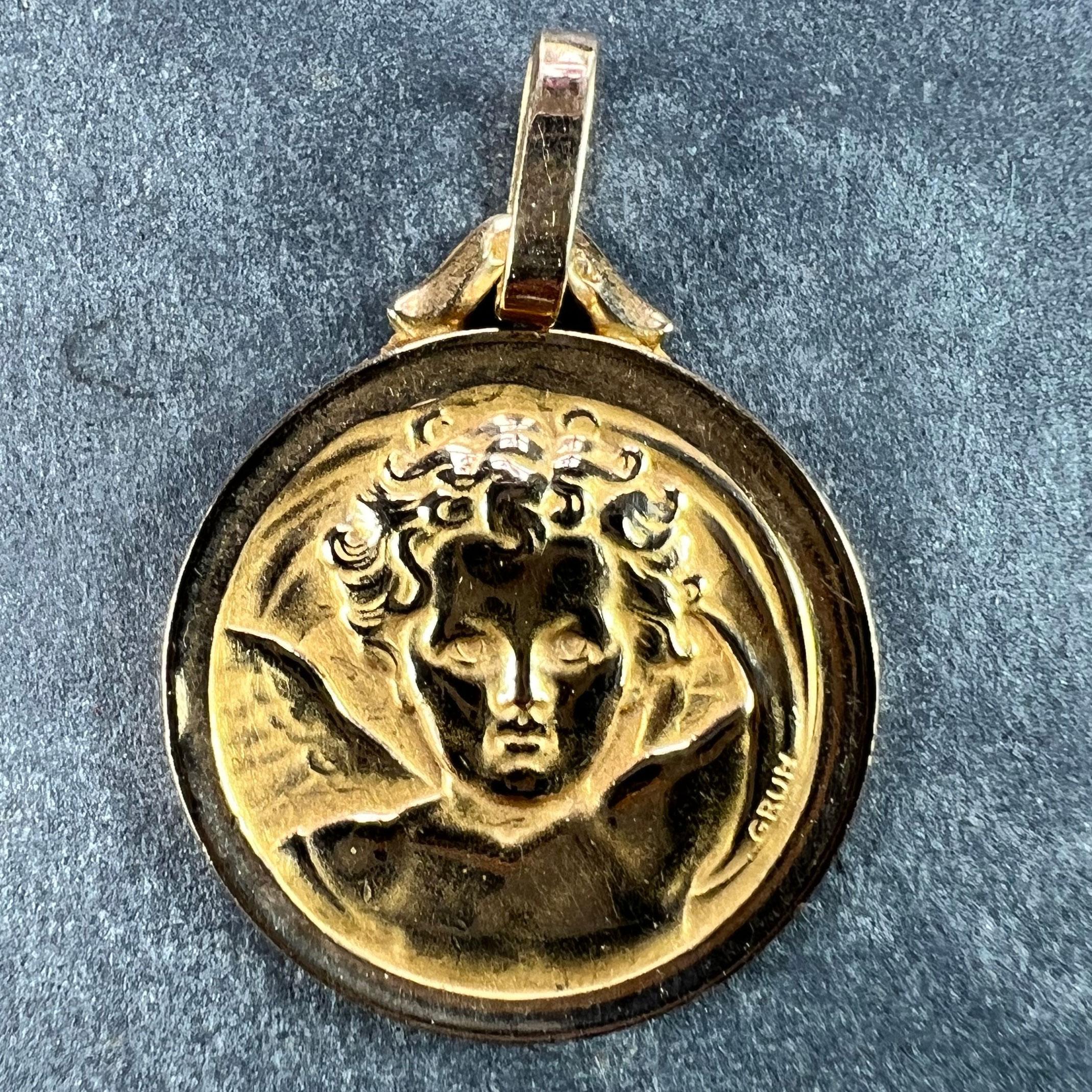 A French 18 karat (18K) yellow gold charm pendant designed as a round medal depicting Raphael’s cherub. Signed Grun. Stamped with the eagle mark for 18 karat gold and French manufacture with maker's mark for Perriat.

Dimensions: 2.2 x 1.8 x 0.11 cm