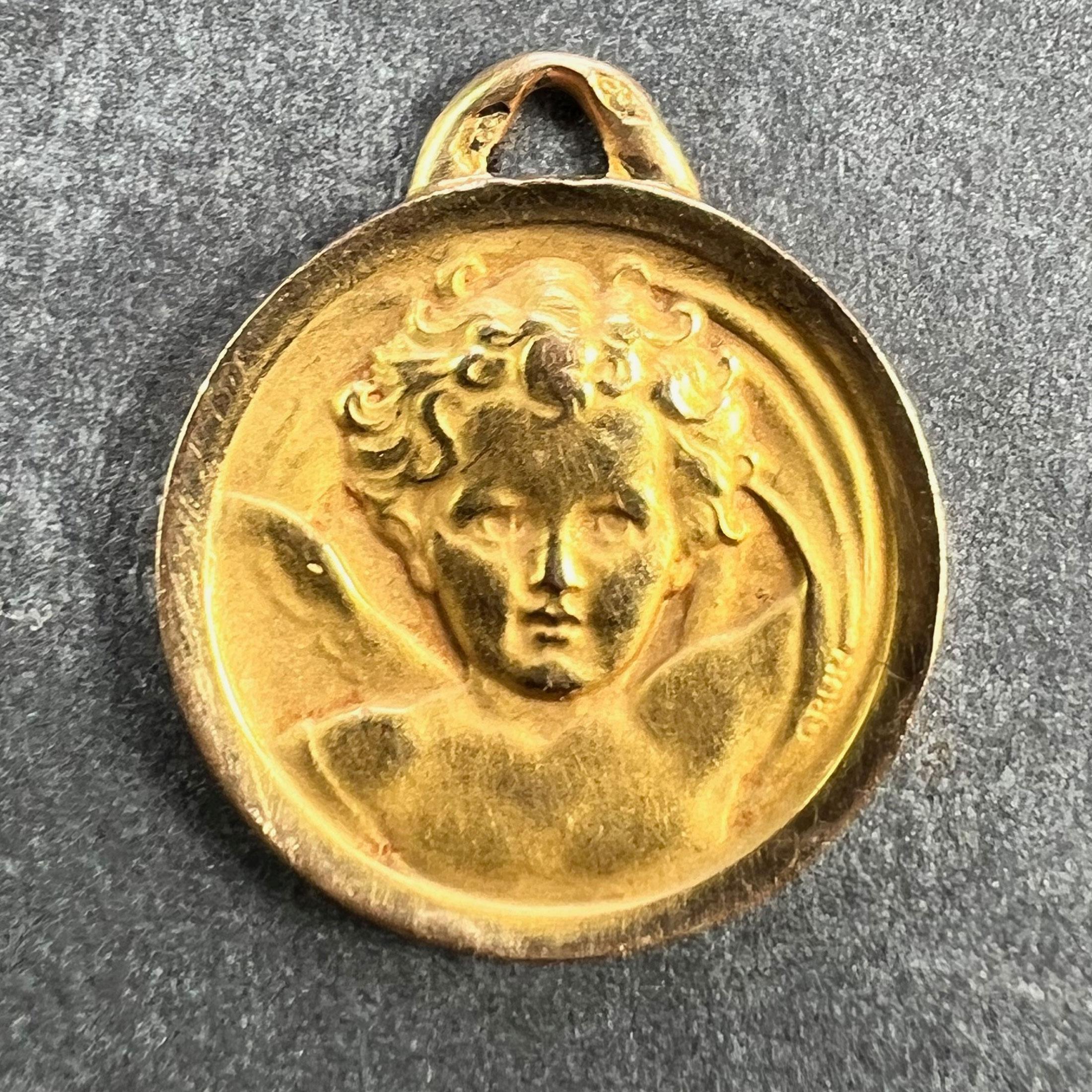 Pendentif breloque français en or jaune 18 carats (18K) conçu comme une médaille ronde représentant l'angelot de Raphael. Signé Grun. Estampillé de la marque de l'aigle pour l'or 18 carats et de la marque de fabrication française pour