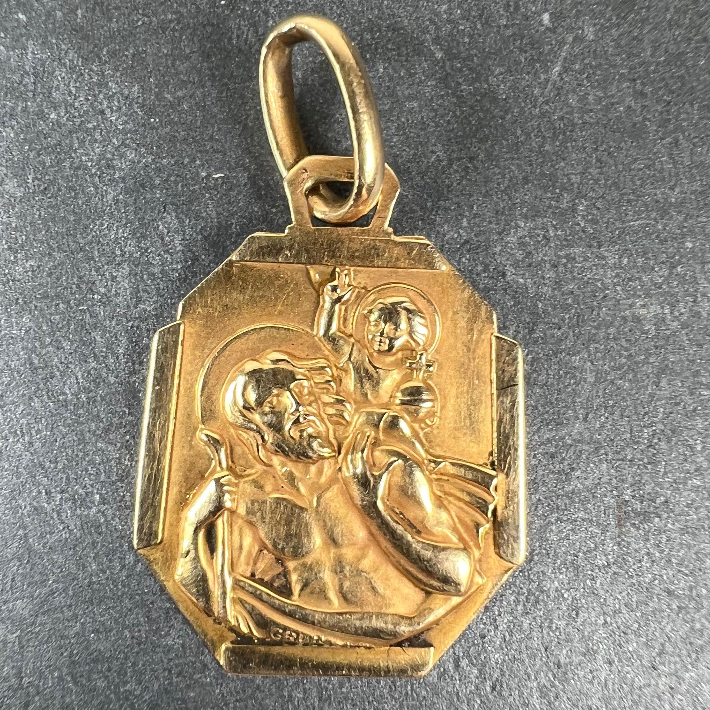 A French 18 karat (18K) yellow gold charm pendant designed as a geometric medal depicting St Christopher carrying the infant Christ across the river set within an octagonal frame. Signed Grun. Stamped with the eagle's head for 18 karat gold and