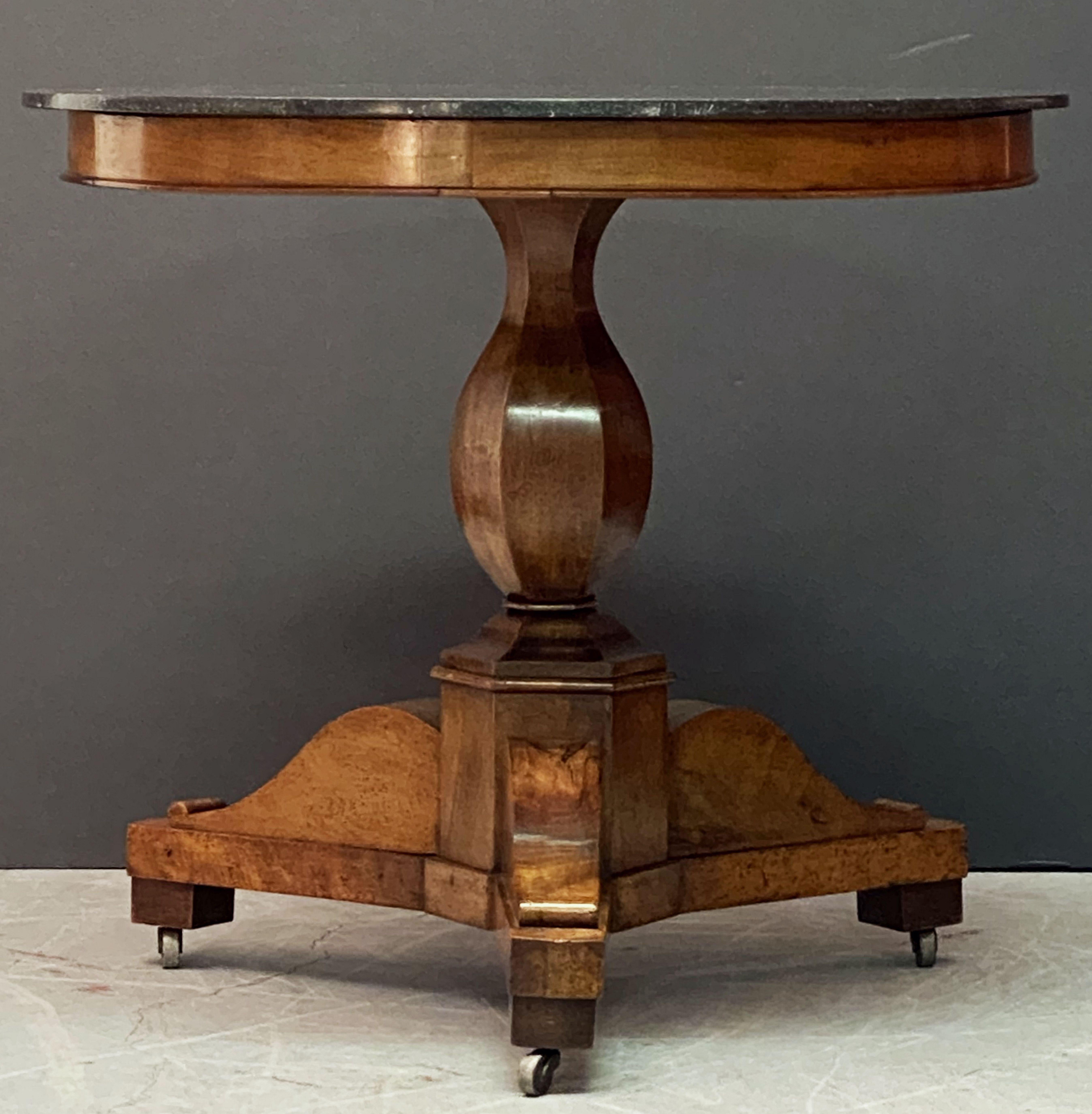 A fine French Guéridon or round center table from the 19th century, a beautifully figured central walnut column supports the circular marble top which is original to the table. Set upon a patinated tri-form base that still retains the original