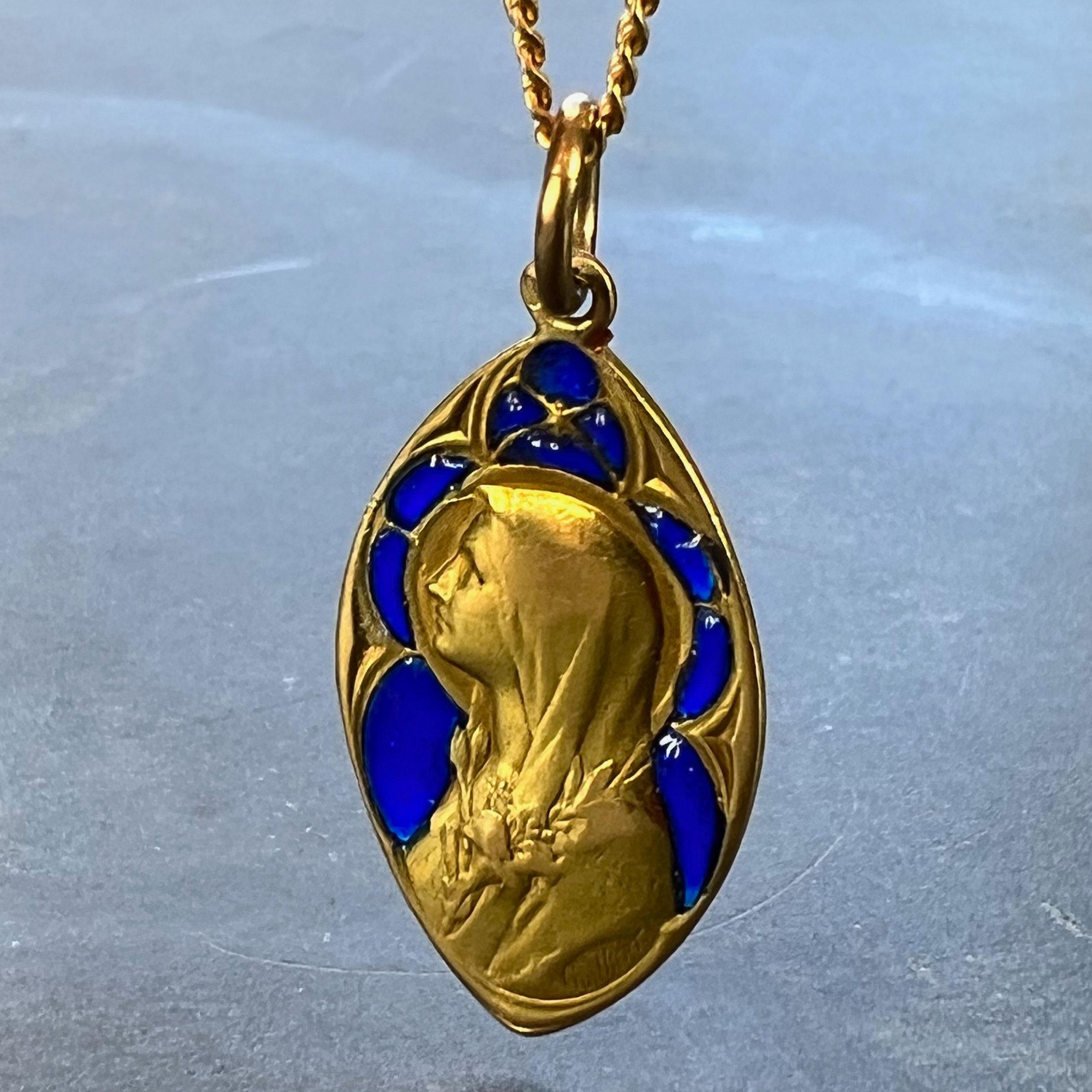 A French 18 karat (18K) yellow gold charm pendant designed as a navette shaped medal depicting the Virgin Mary with plique a jour blue enamel surround. Signed Guilbert, stamped with the eagle’s head for 18 karat gold and French manufacture, and a