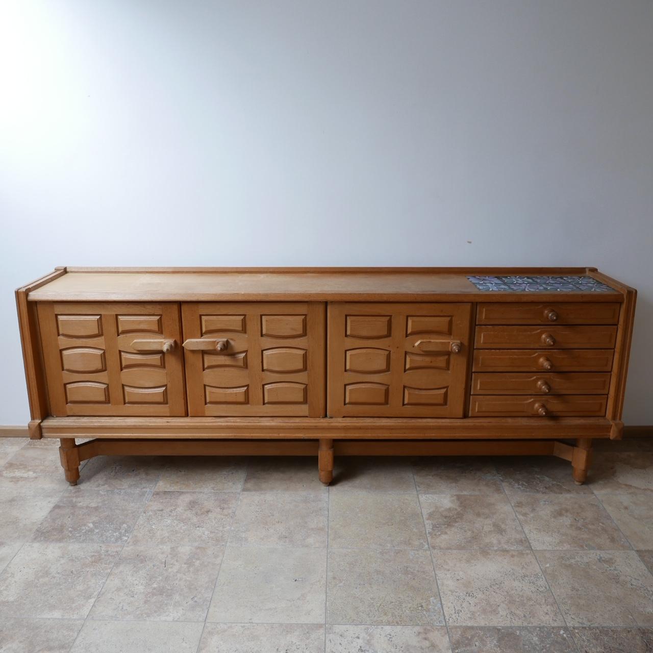 A large credenza by French design legends Guillerme et Chambron. 

France, c1960s. 

Oak with original ceramic tiles retained. These could be replaced for marble, mirrored glass or smoked glass if they are not to taste. Brass hinges. 

Three