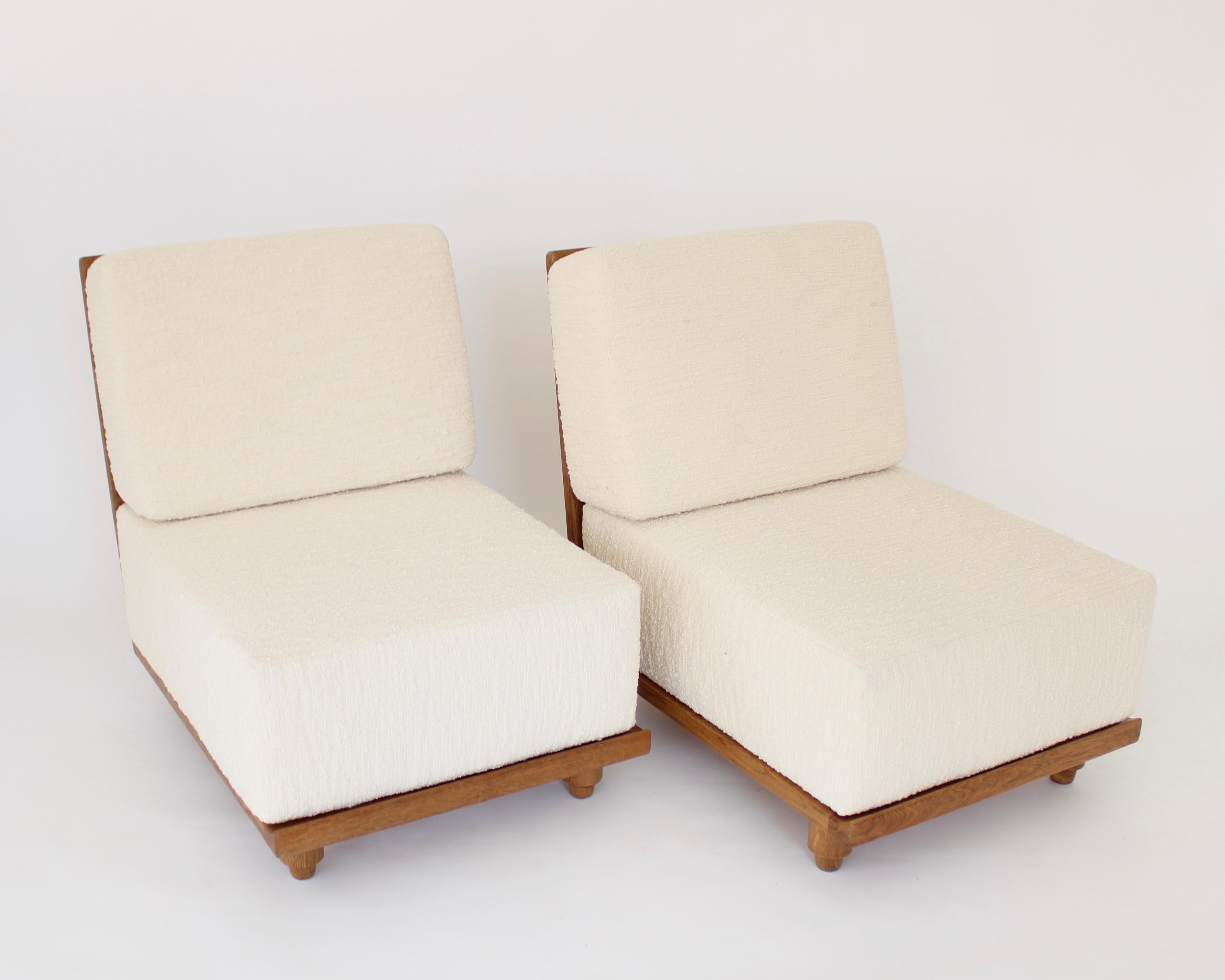 Two extraordinary French Gullerme et Chambron or Guillerme and Chambron lounge chairs in oak for Votre Maison. 
This pair of the model Elmyre lounge chairs have a very deep and thick cushion that raises the sitter off the floor as a more typical