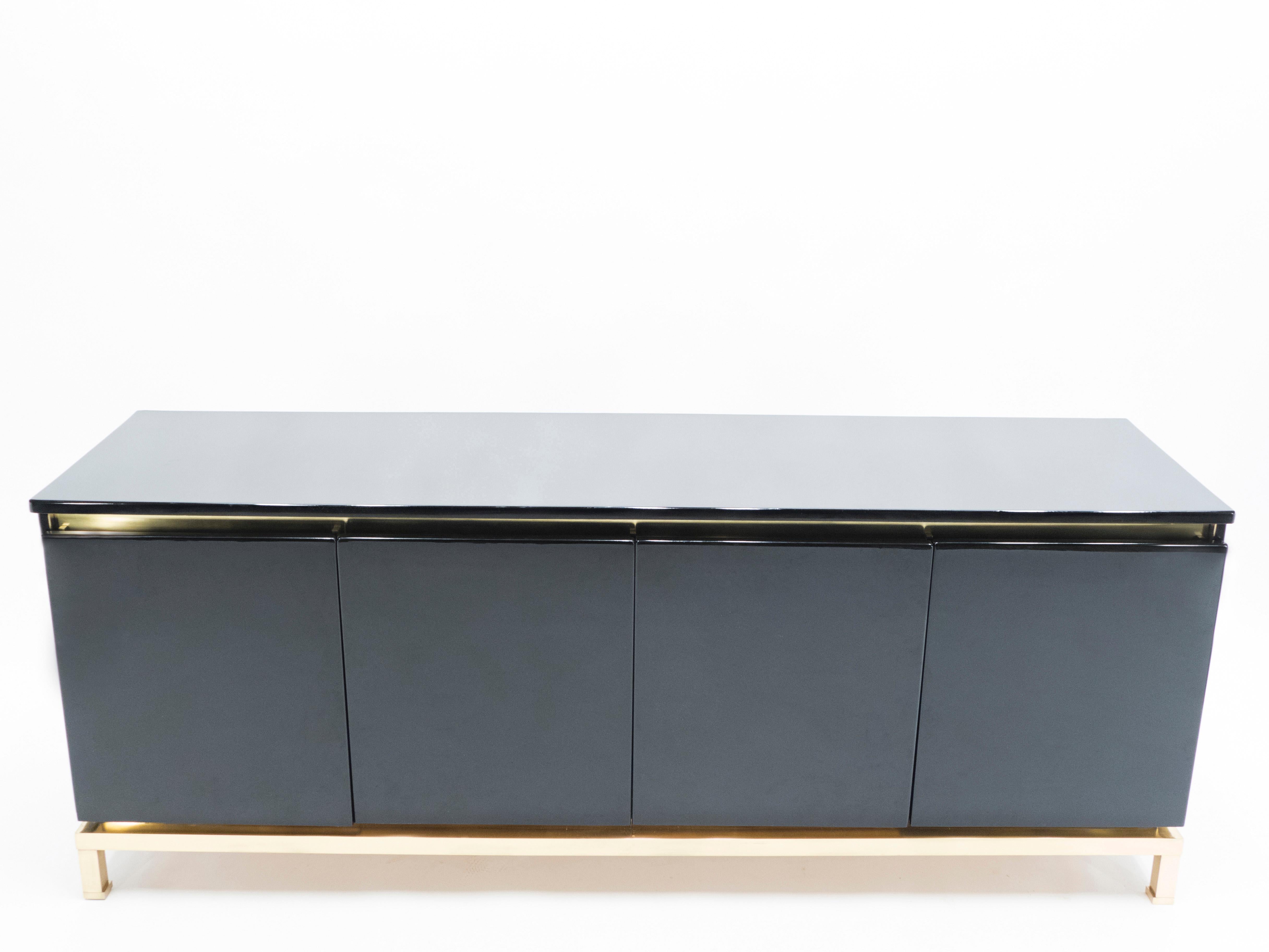A timeless vintage piece, this midcentury sideboard feels imposing and glamourous, with thick, straight lines of brass adorning its exterior of reflective black lacquer. Glossy black lacquer, paired with bright brass accents en feet, feels crisp and